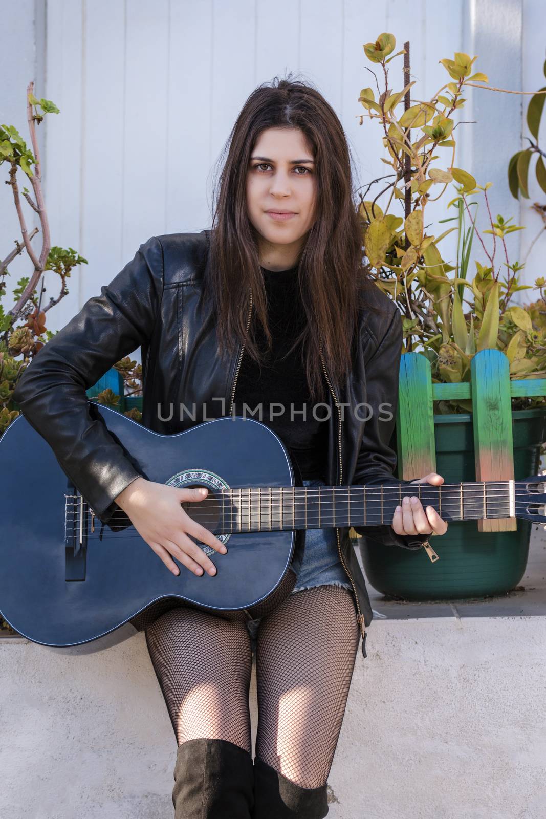 Close view of a beautiful young woman with classic guitar on the streets of the city.