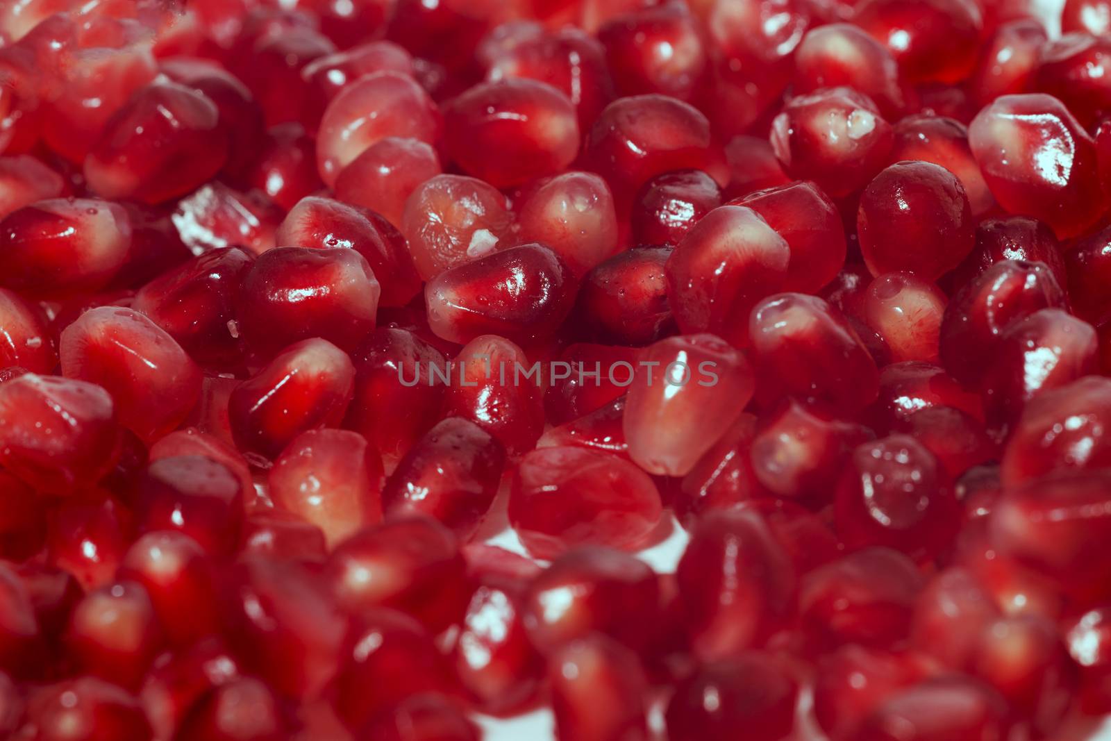 Close up view of tasty pommegranate fruit seeds isolated on a white background.