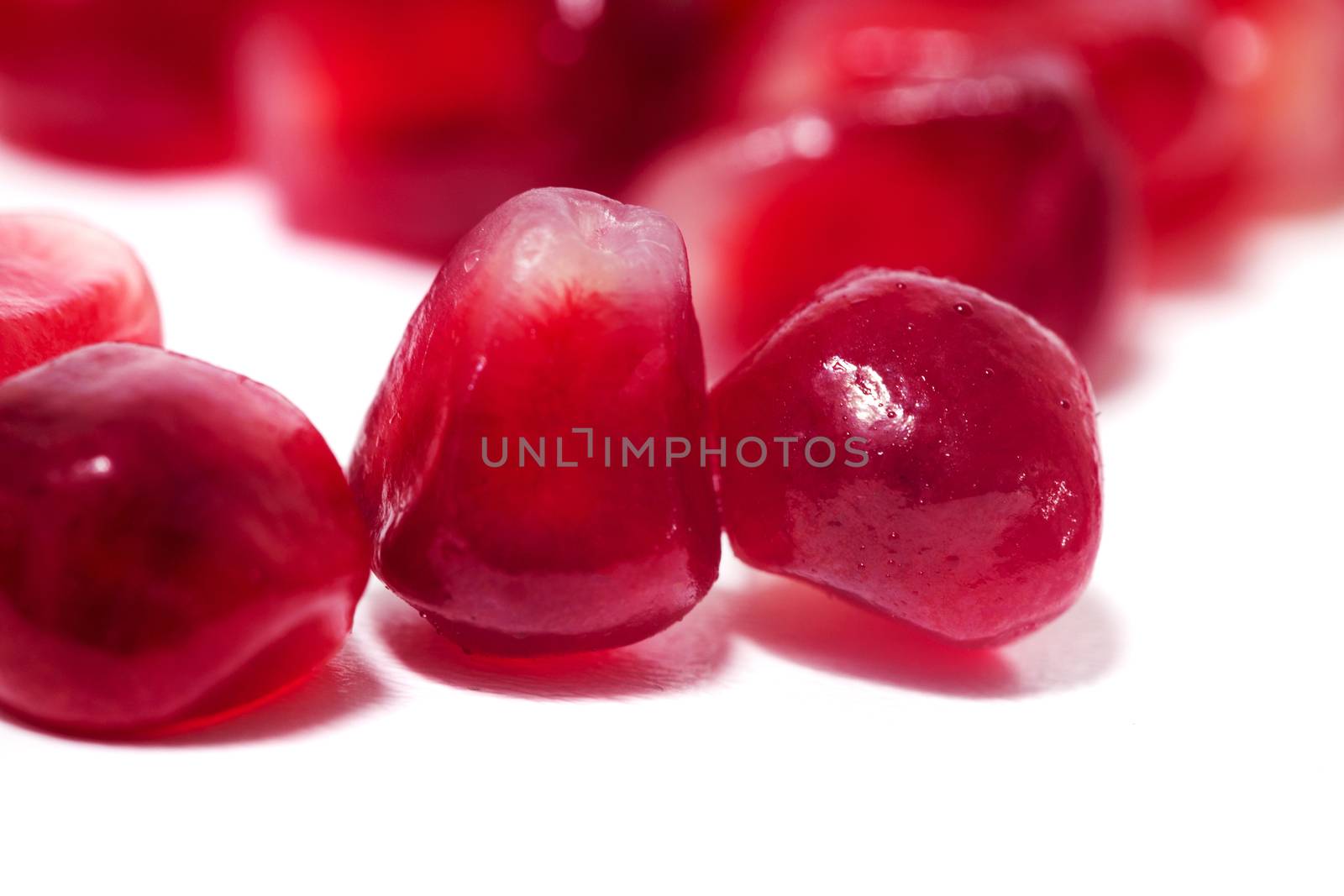 Close up view of tasty pommegranate fruit seeds isolated on a white background.