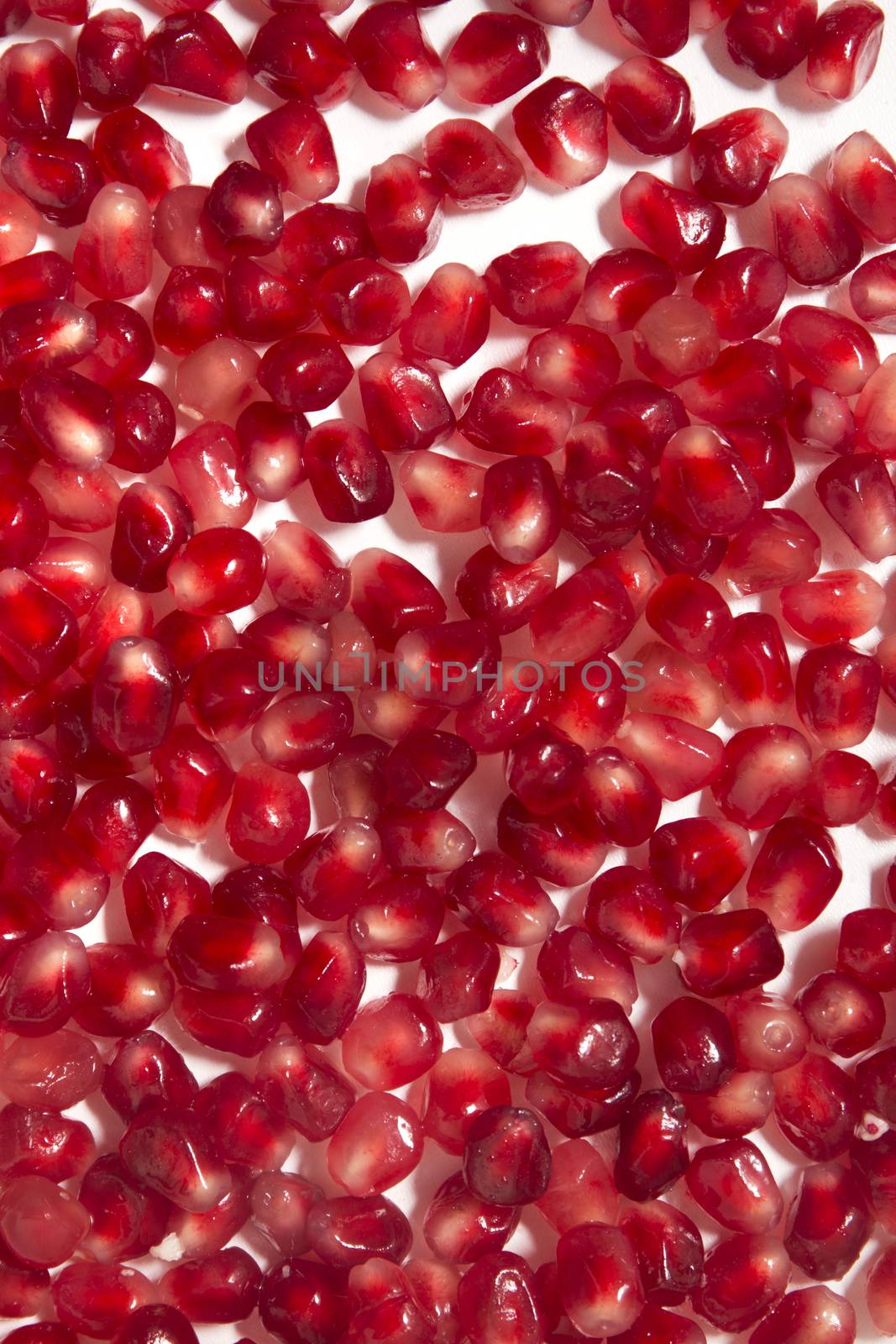 Close up view of tasty pommegranate fruit seeds isolated on a white background.