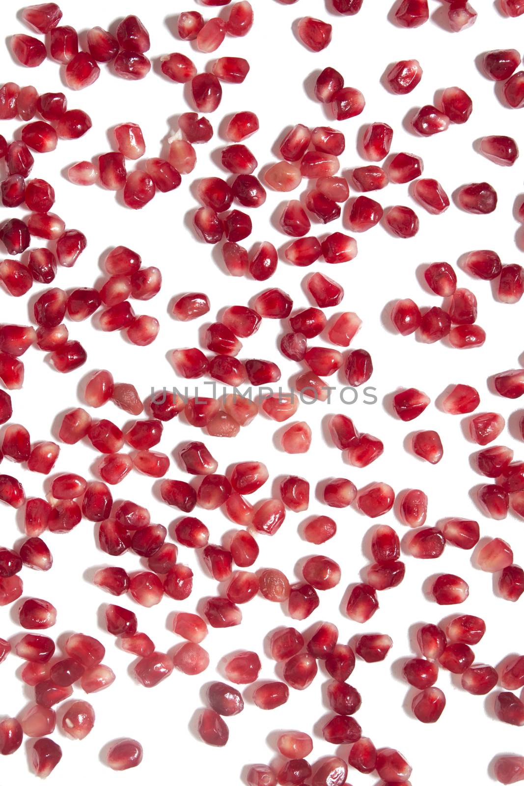 Close up view of tasty pommegranate fruit seeds isolated on a white background.