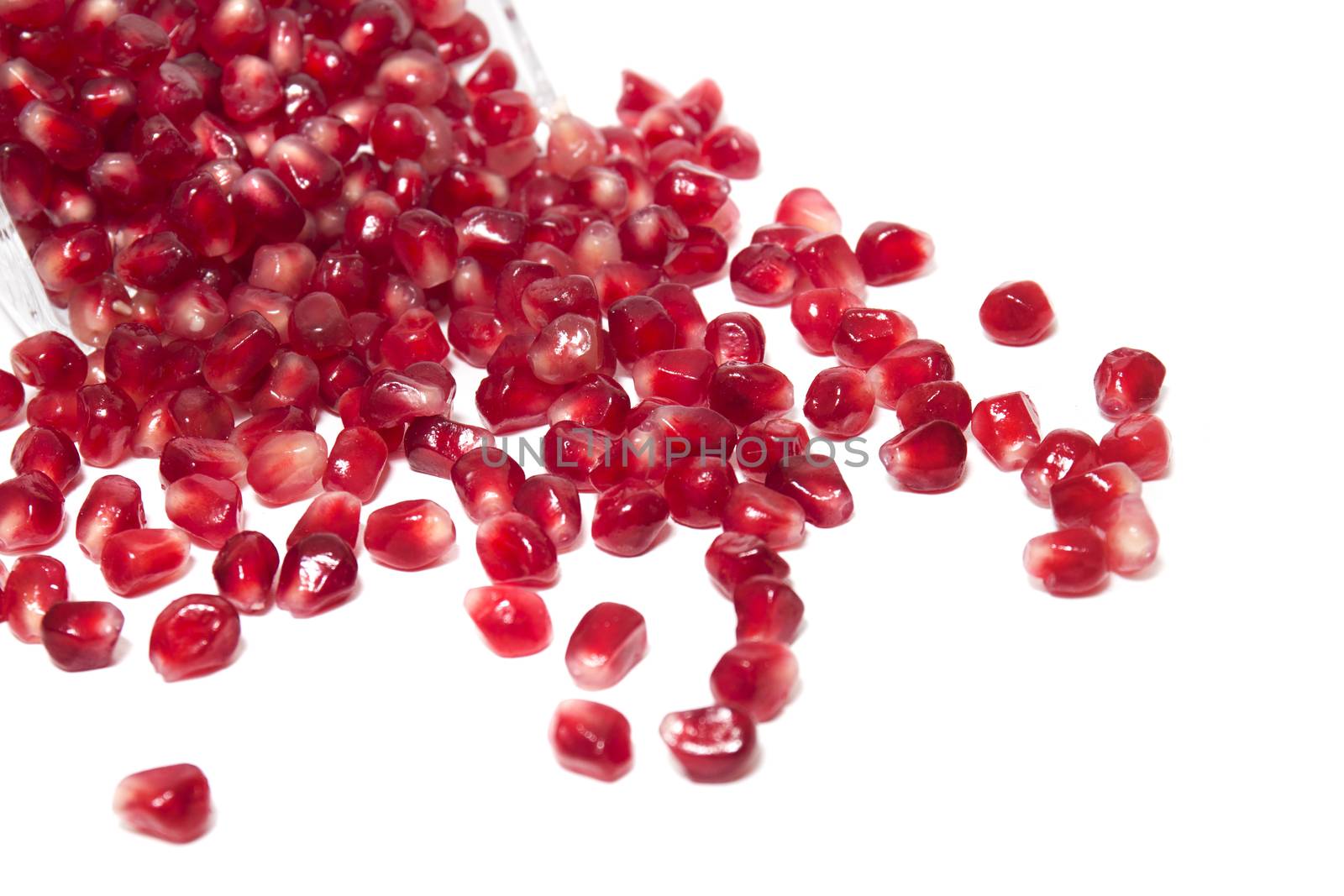 Close up view of tasty pommegranate fruit seeds isolated on a white background.