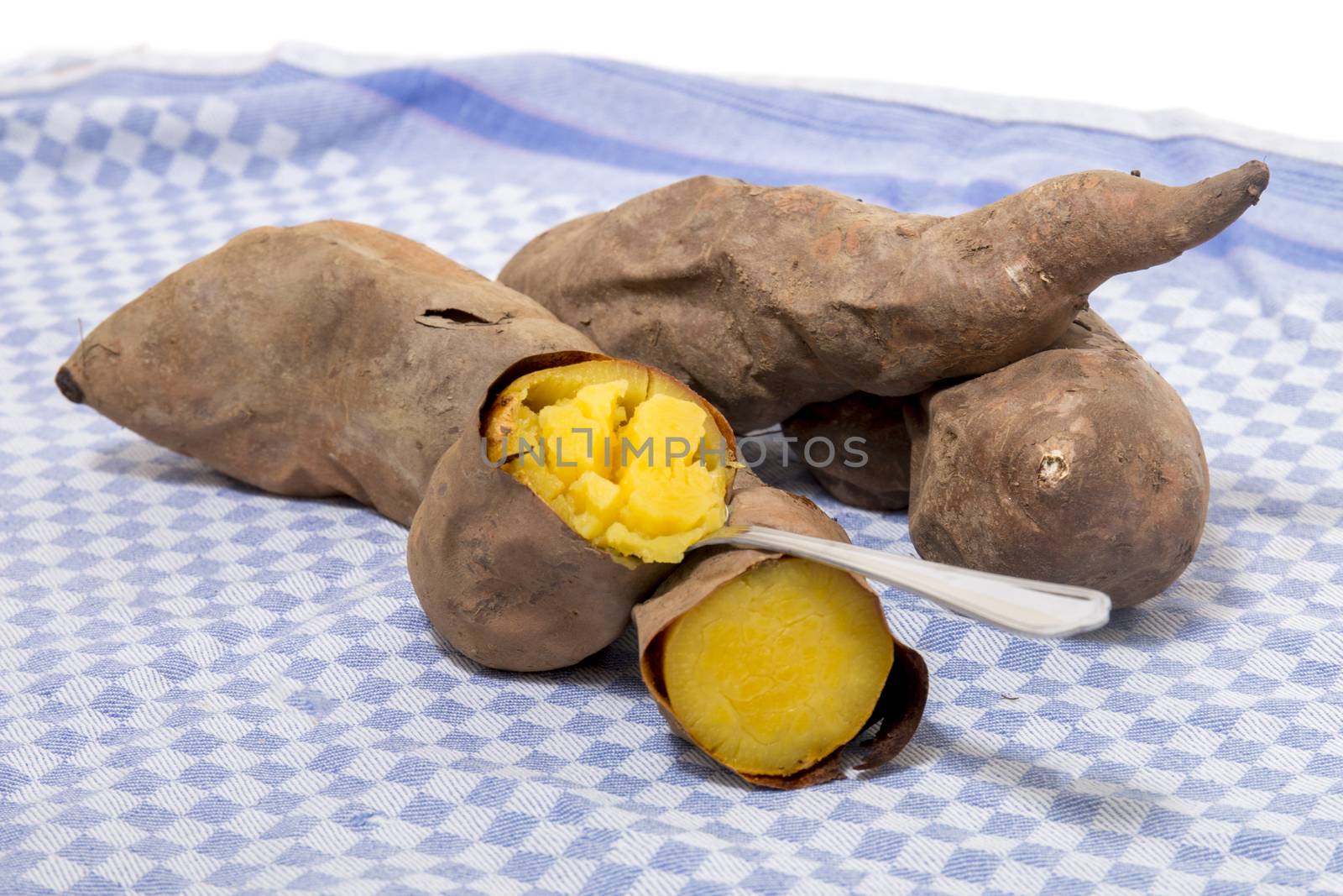Cooked oven sweet potatoes on a table cloth fabric.