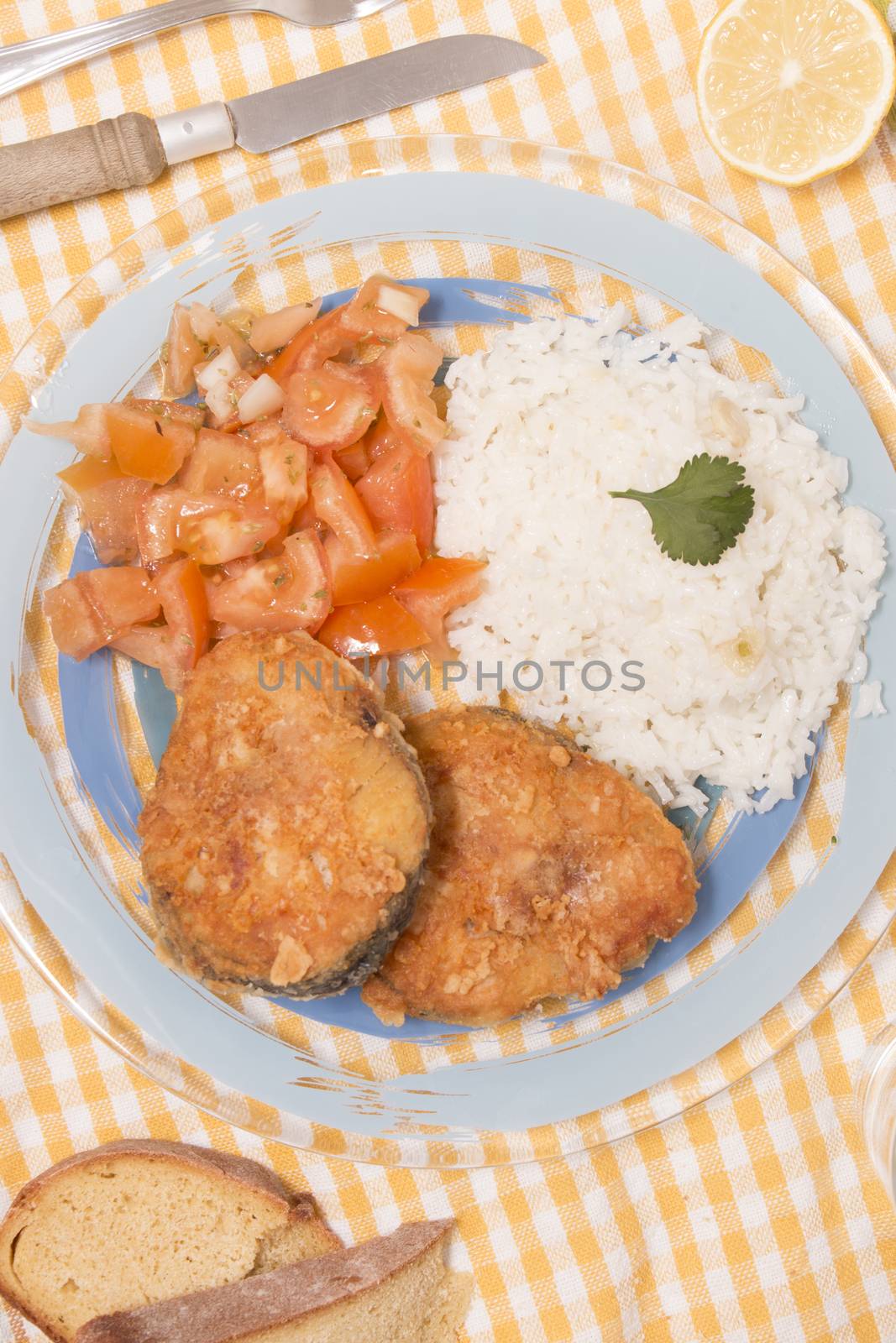 Fried hake fish with rice and tomato salad.