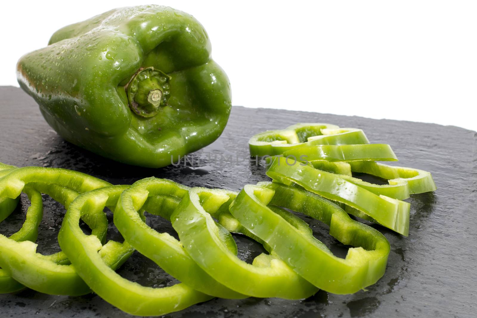 green bell peppers on a black stone of schist, wet and sliced.