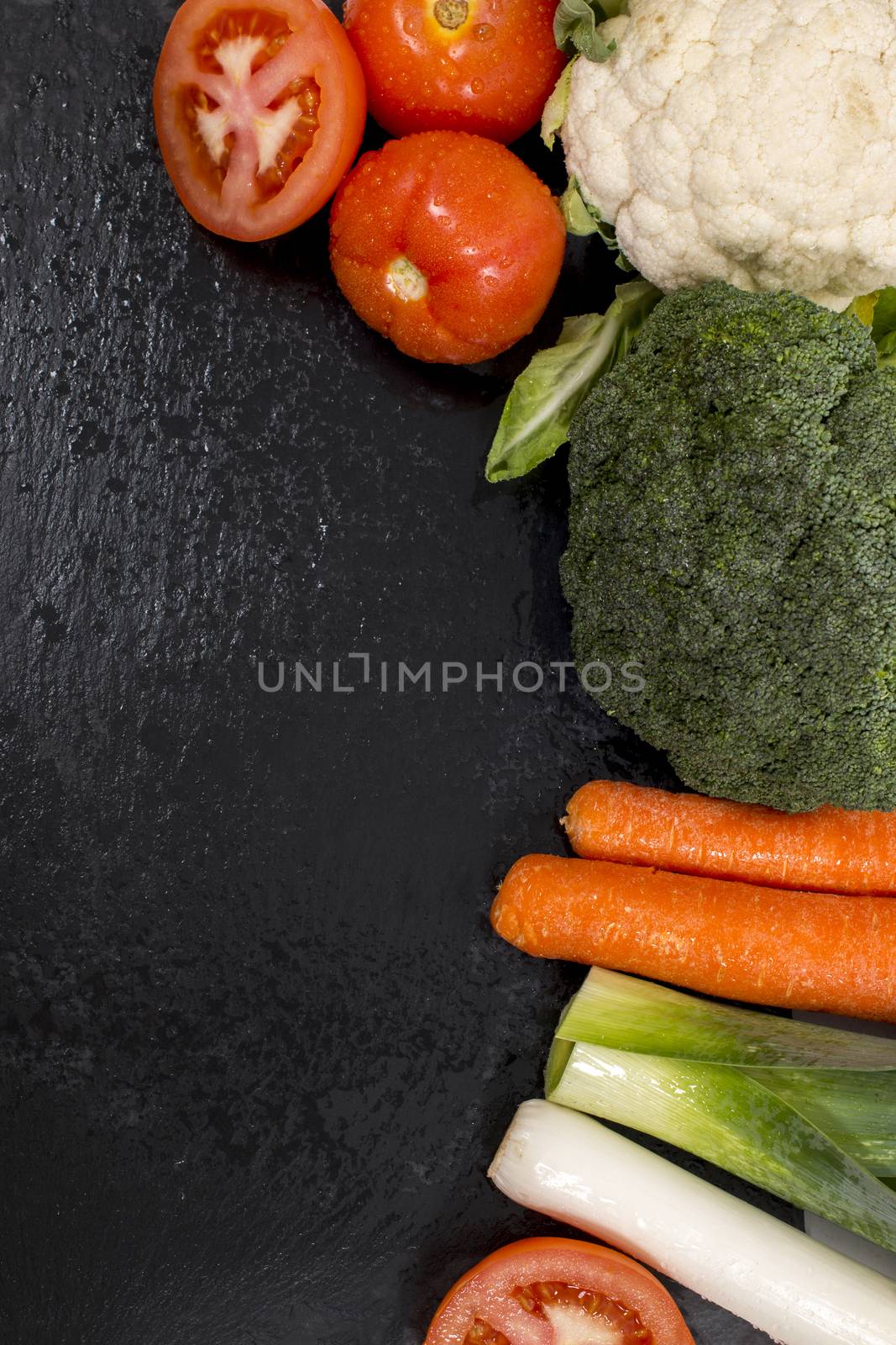 Mixed wet vegetables on top of a black slab of schist.