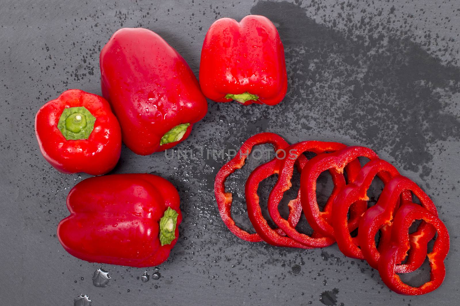 red bell peppers on a black stone of schist, wet and sliced.