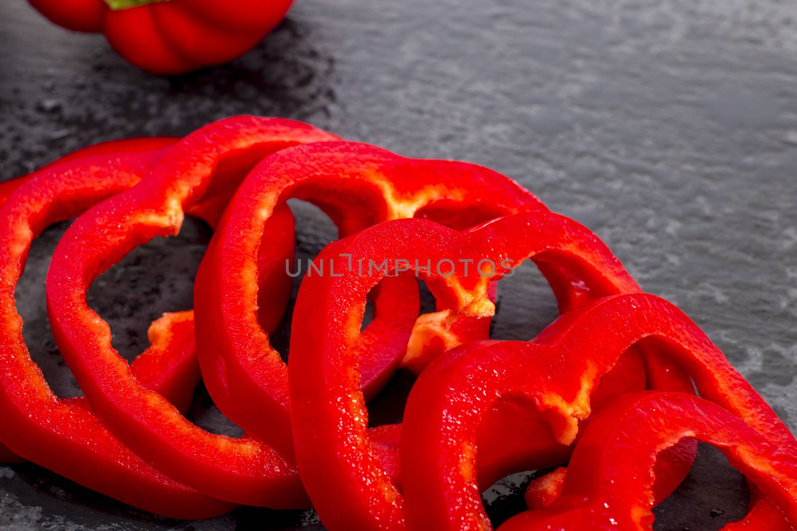 red bell peppers on a black stone of schist, wet and sliced.