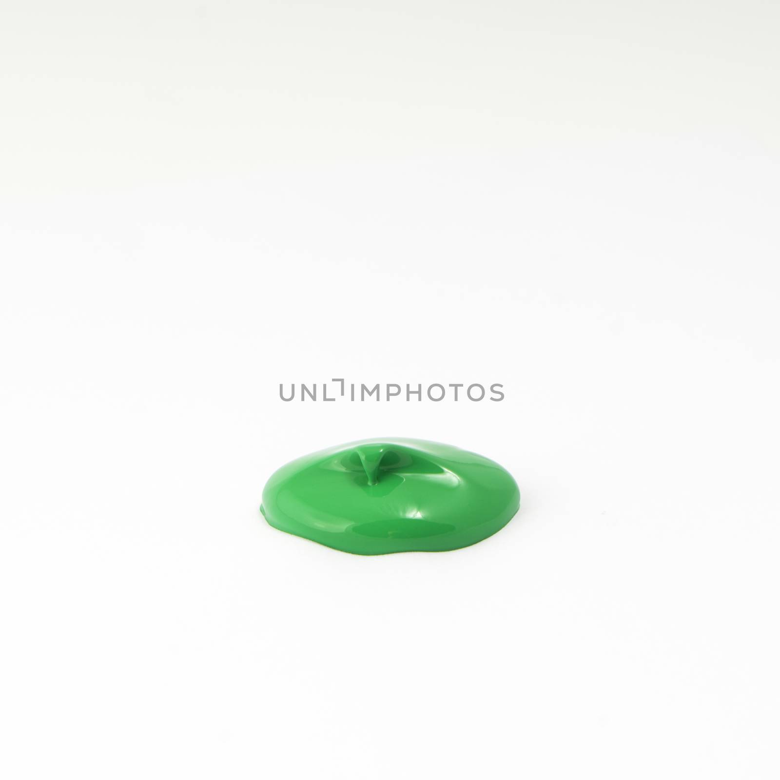 a drop of acrylic green color on a white surface