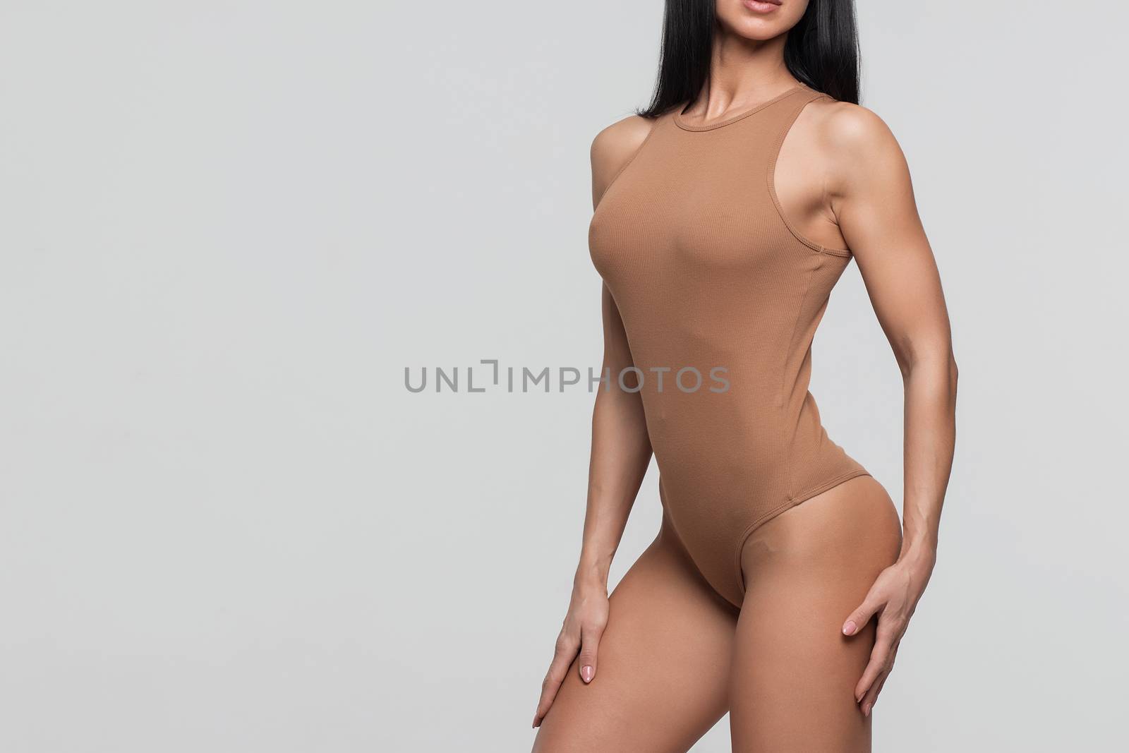 Slim tanned woman's body over gray background