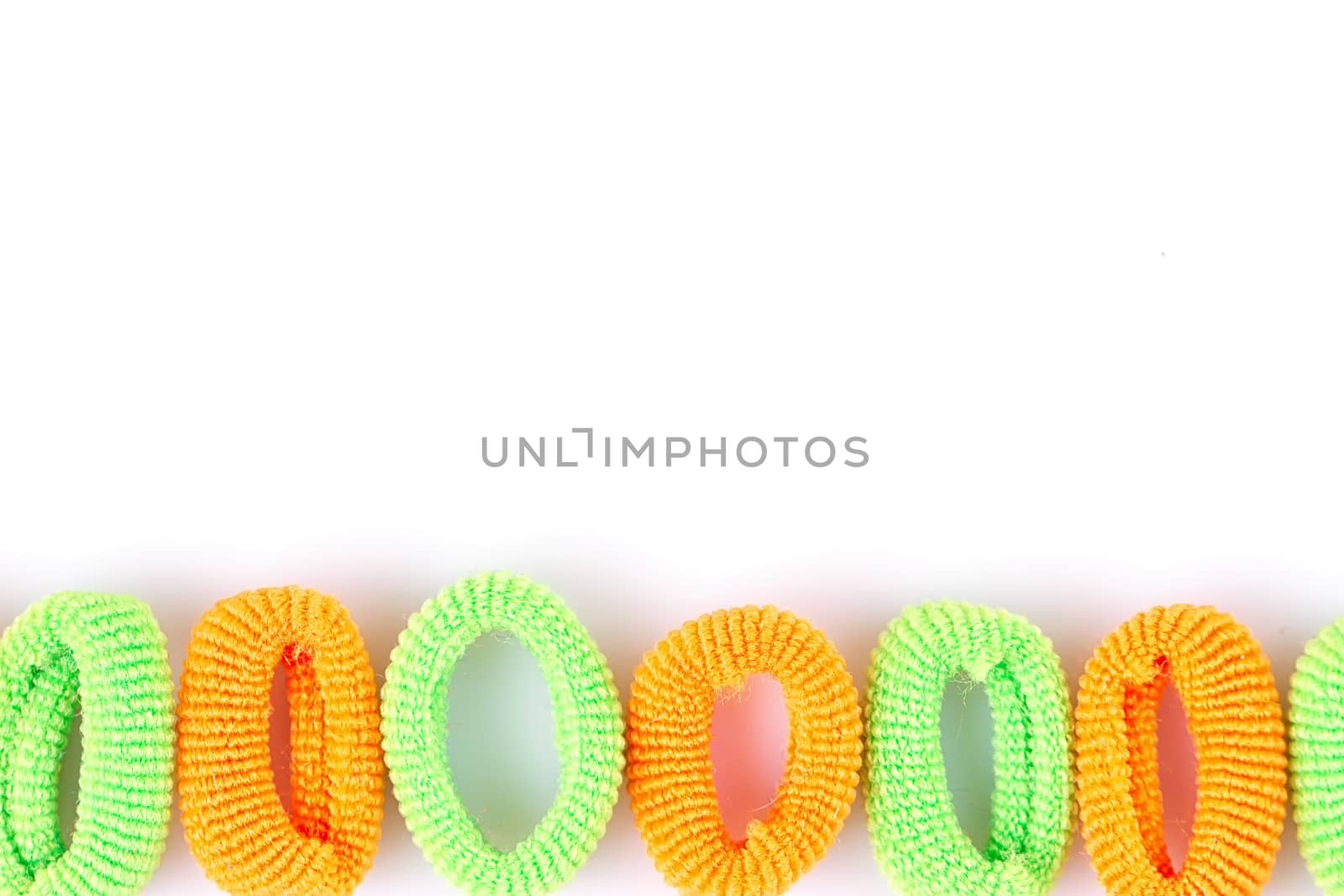 Green and orange soft hair bands are lined with a line on a white background
