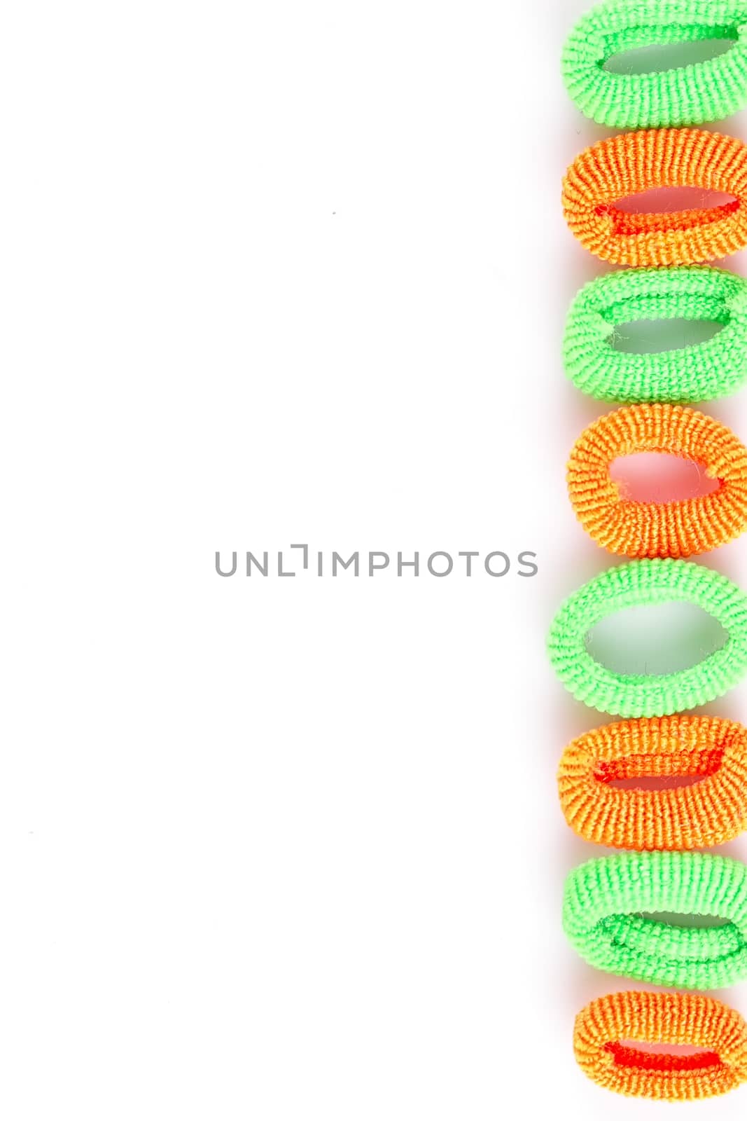 Green and orange soft hair bands are lined with a line on a white background