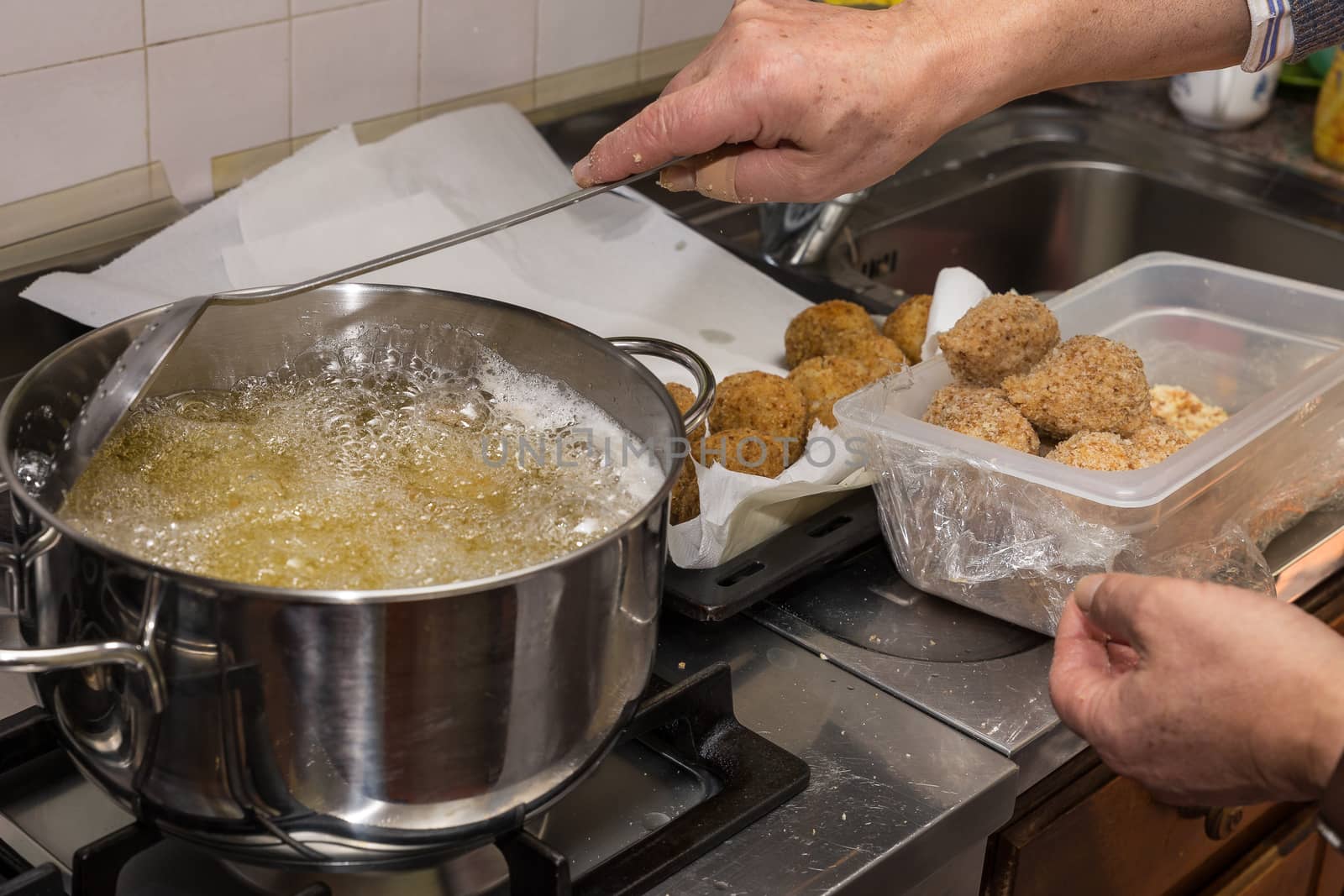 Chef frying food in flaming pan on gas hob in commercial kitchen.