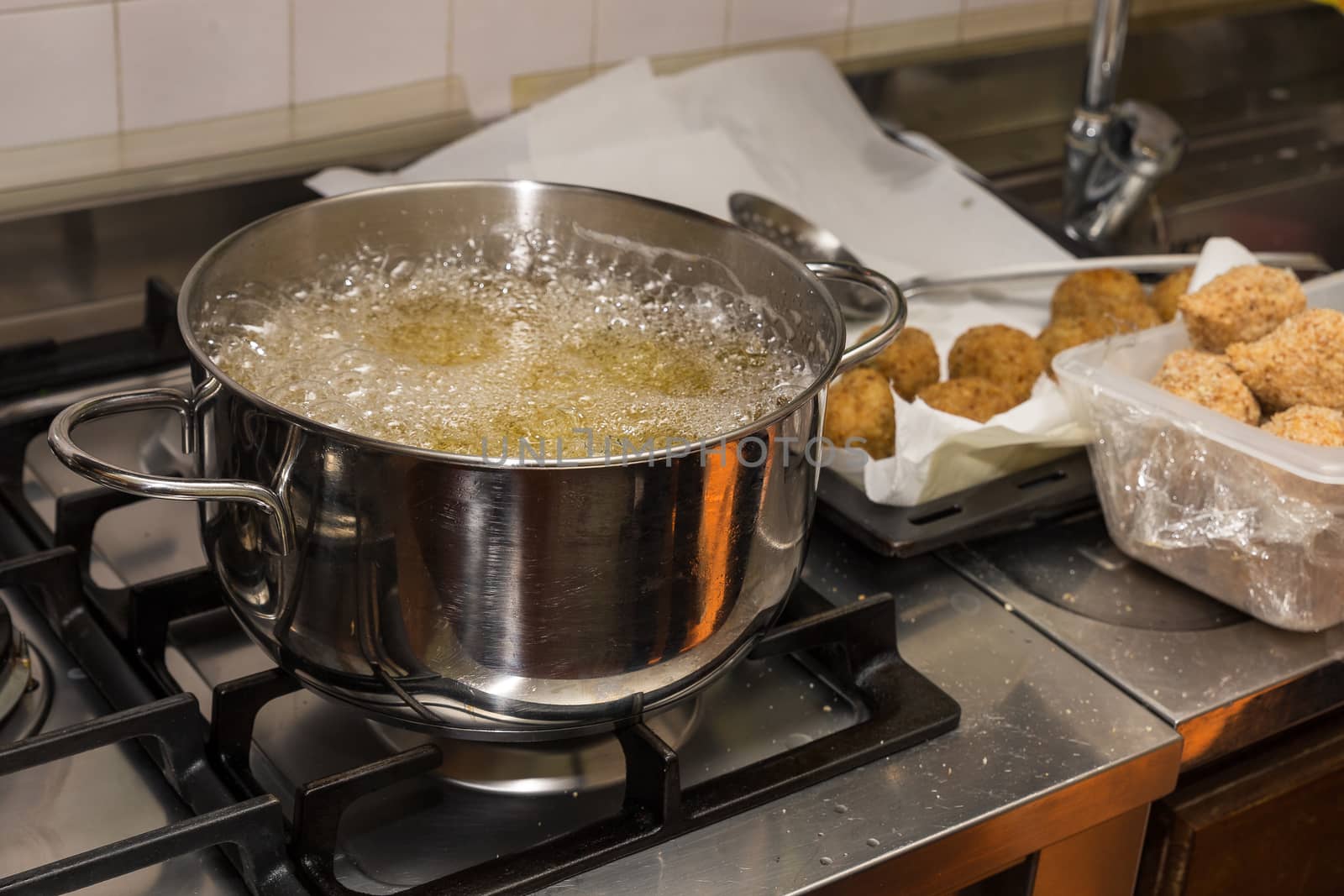 Chef frying food in flaming pan on gas hob in commercial kitchen.