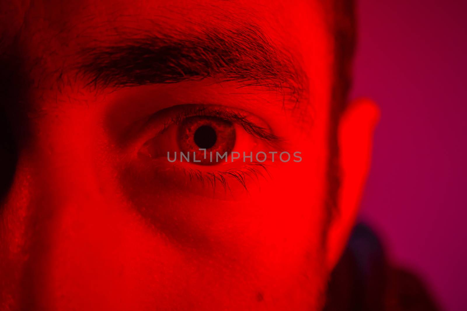 Close up on man face with mysterious facial expression. Portrait of suspicious young man.