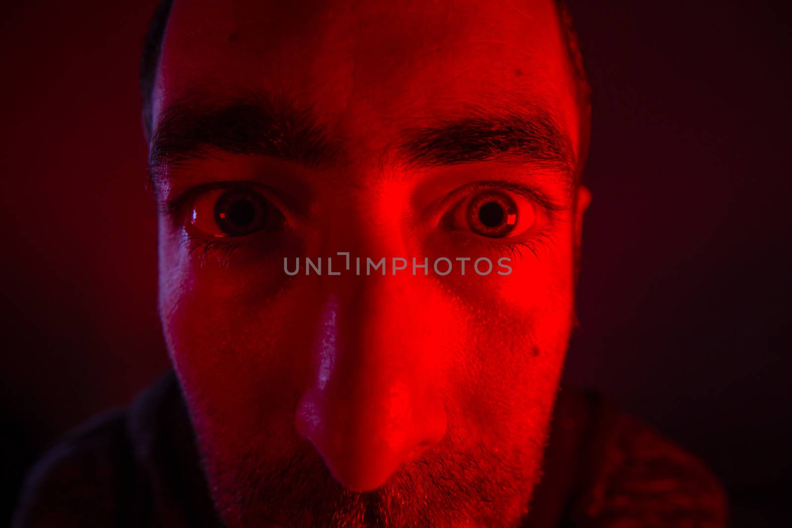 Close up on man face with suspicious or angry facial expression. Portrait of shock young man.