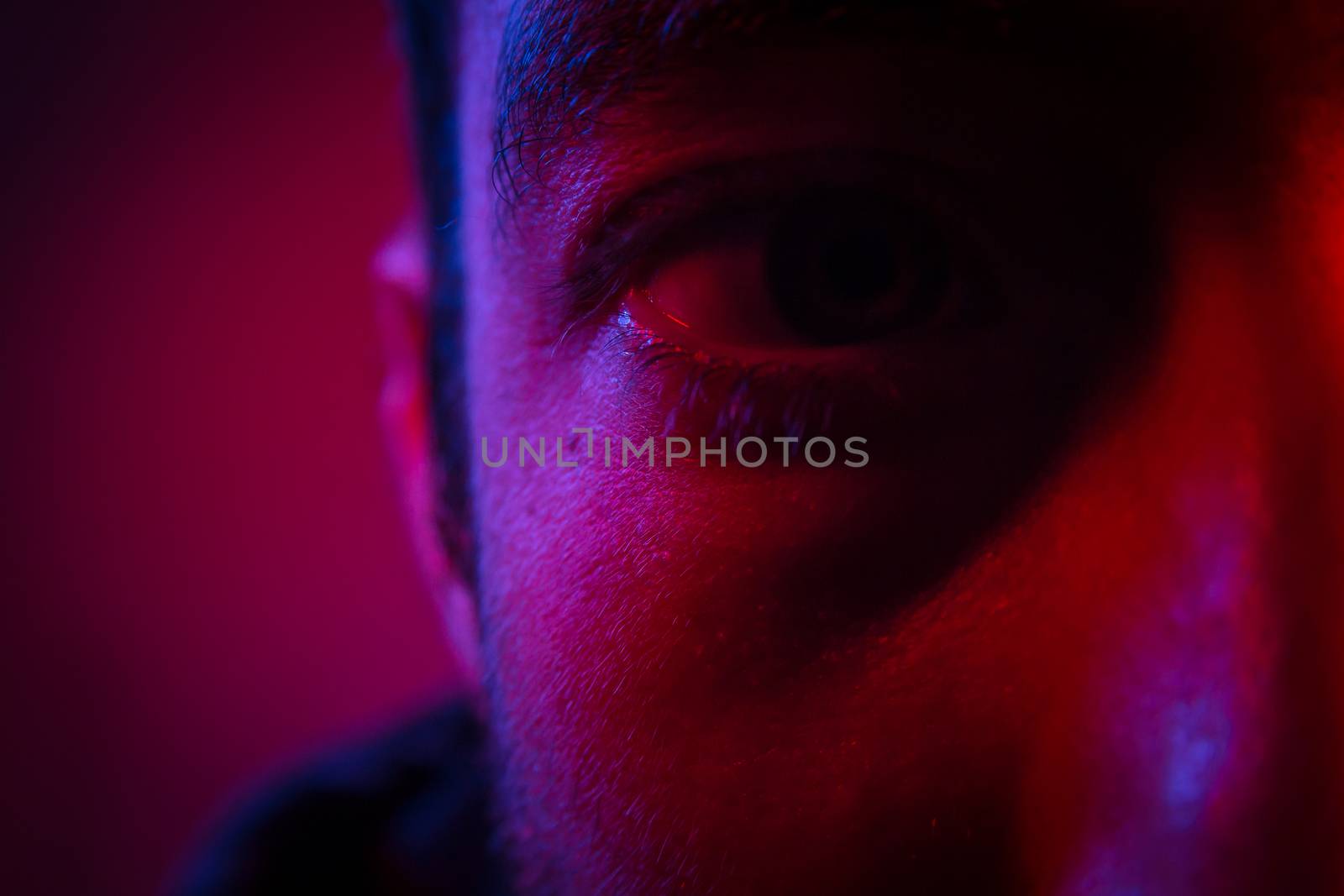 Close up on man face with mysterious facial expression. Portrait of suspicious young man.