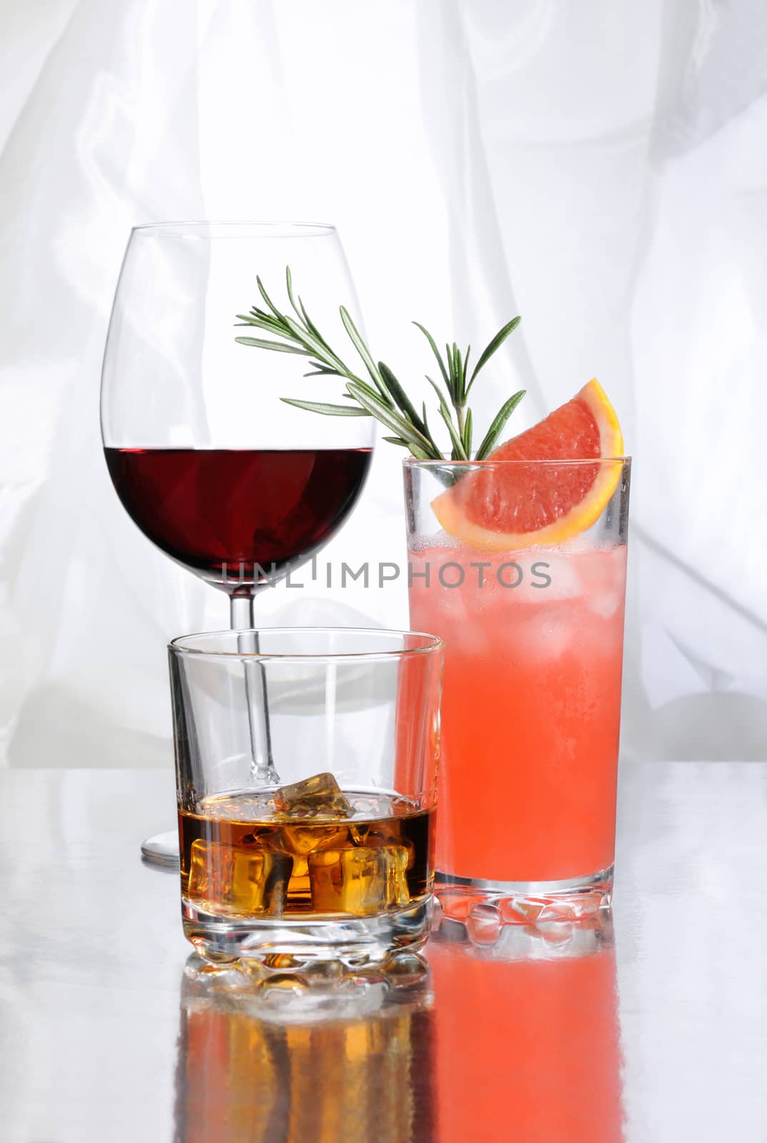 Paloma cocktail in Collins Glass, Whiskey in rocks glass with  ice cubes, red wine in Bordeaux-shaped glass. Drinks  on a light background.