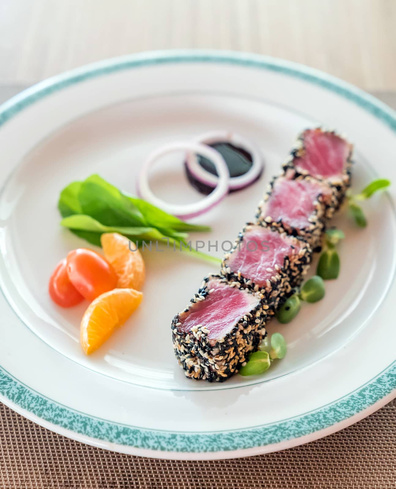 Seared tuna with sesame seeds with green salad on white plate