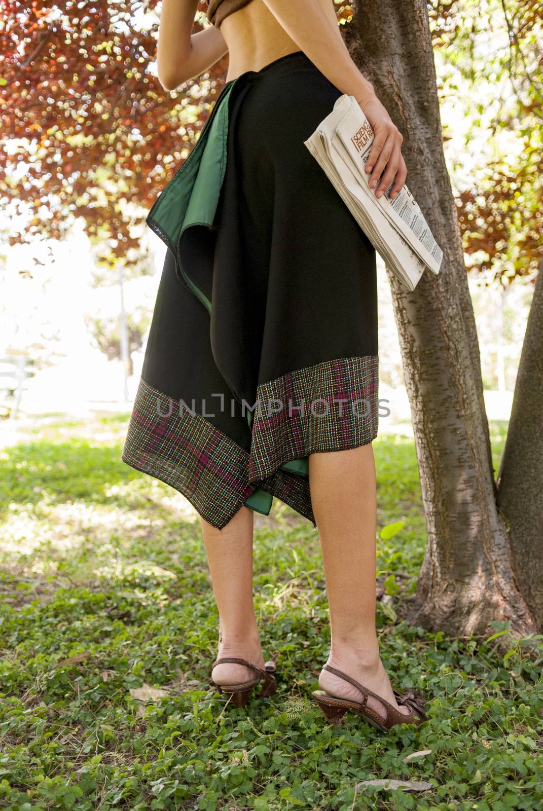 young woman holding a newspaper in the park