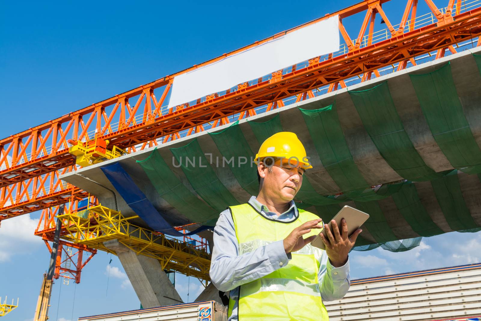 Male Architect or Engineer working with Digital Wireless Tablet beside Autobahn or Expressway Construction site as Technology Project Development