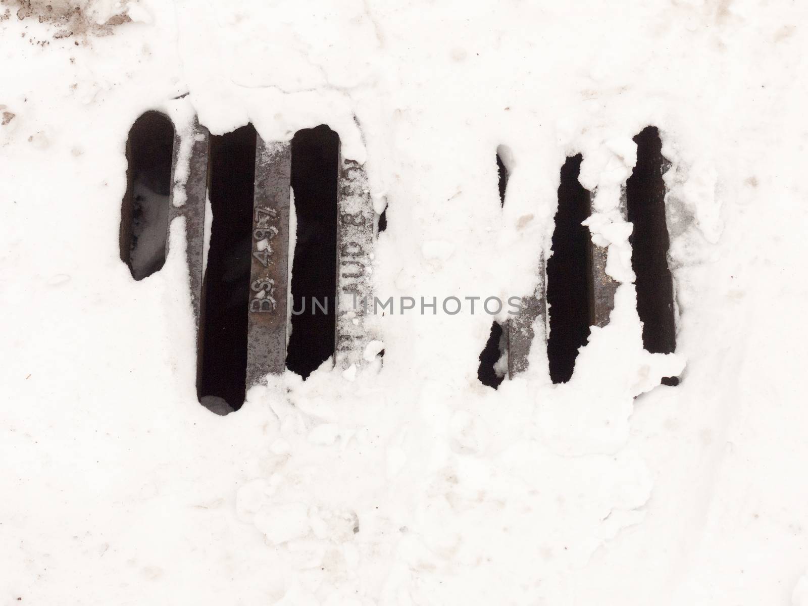 white snow on metal grate outside pavement road ; essex; england; uk