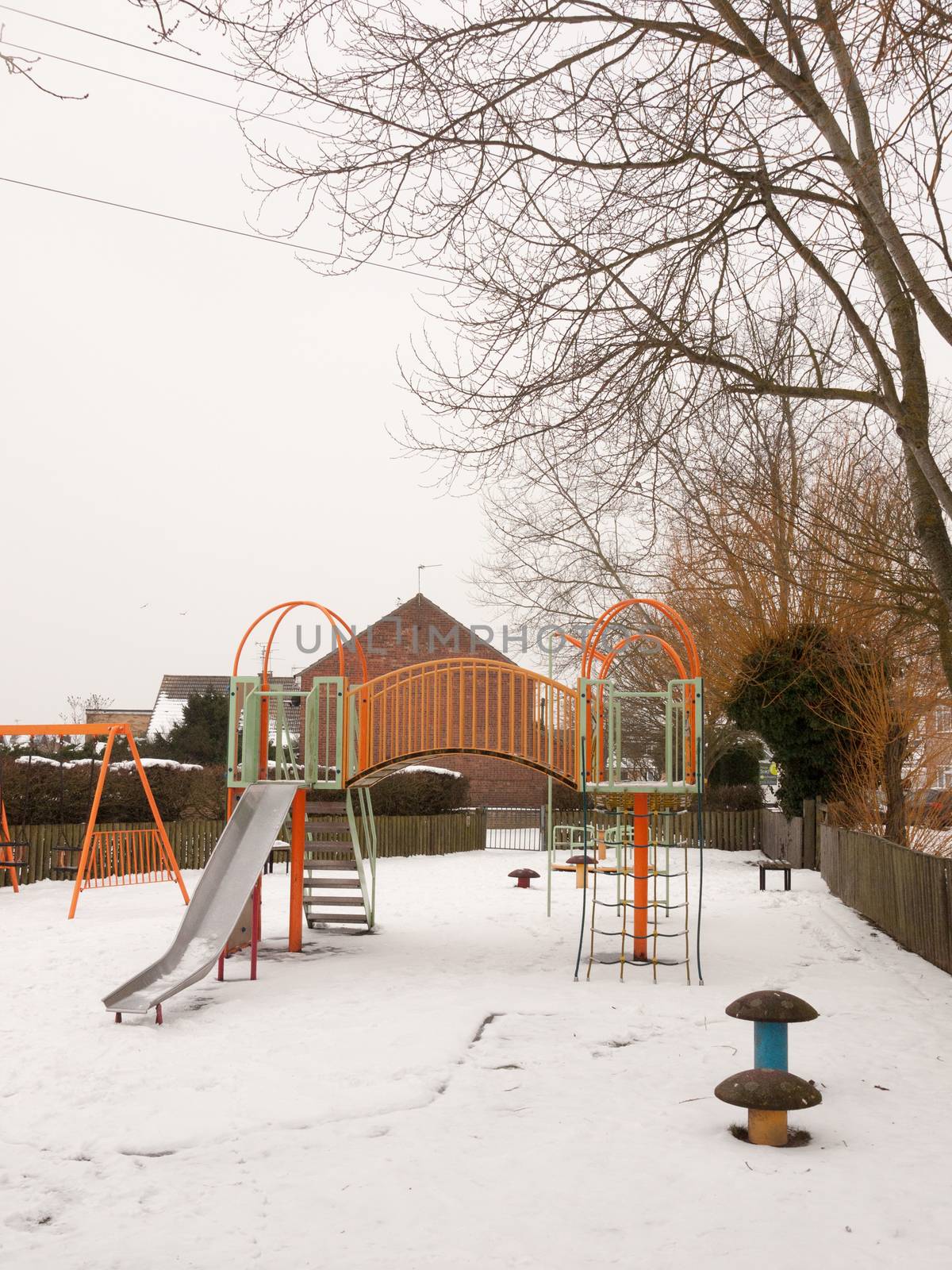 school children's playground park climbing frame outside snow winter; essex; england; uk