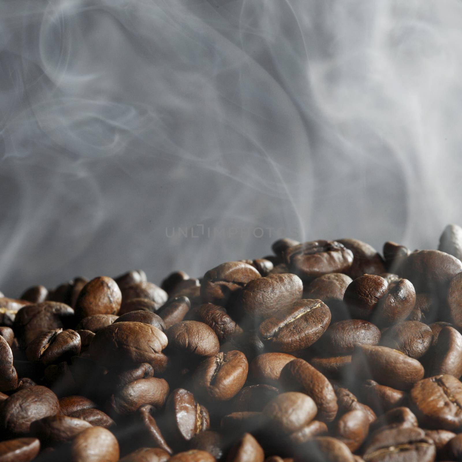 Hot roasted coffee beans and steam on black