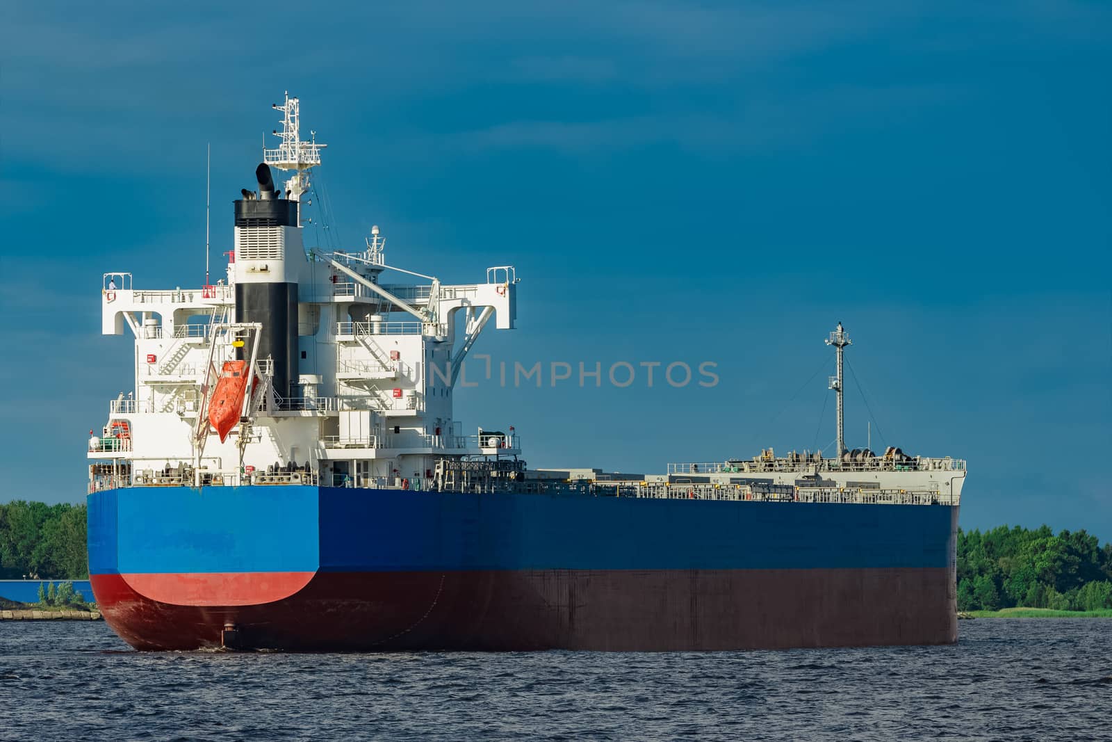 Merchandise import. Large blue cargo ship moving to Riga port