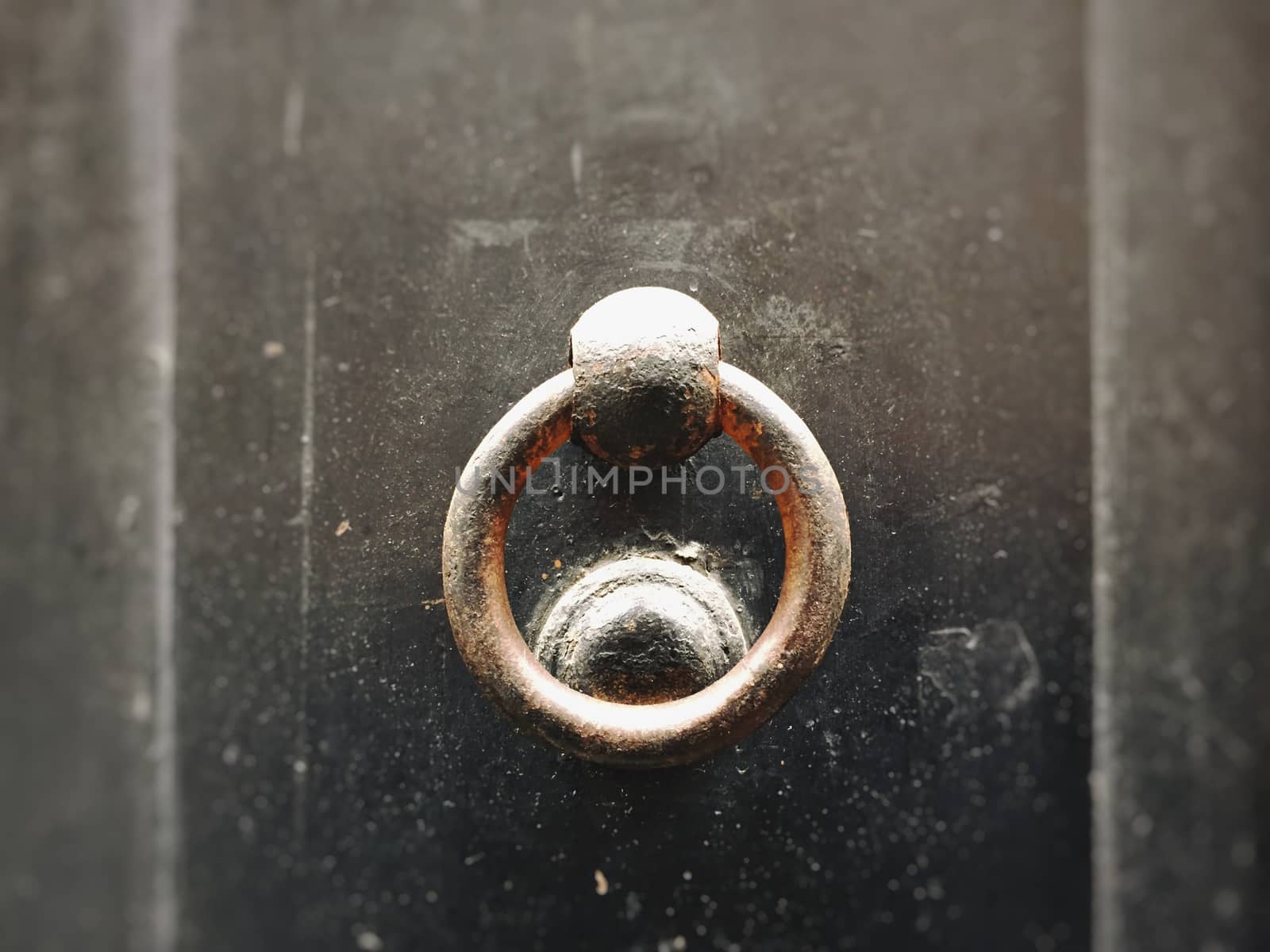 close up of an ancient round clapper on a dark wooden door