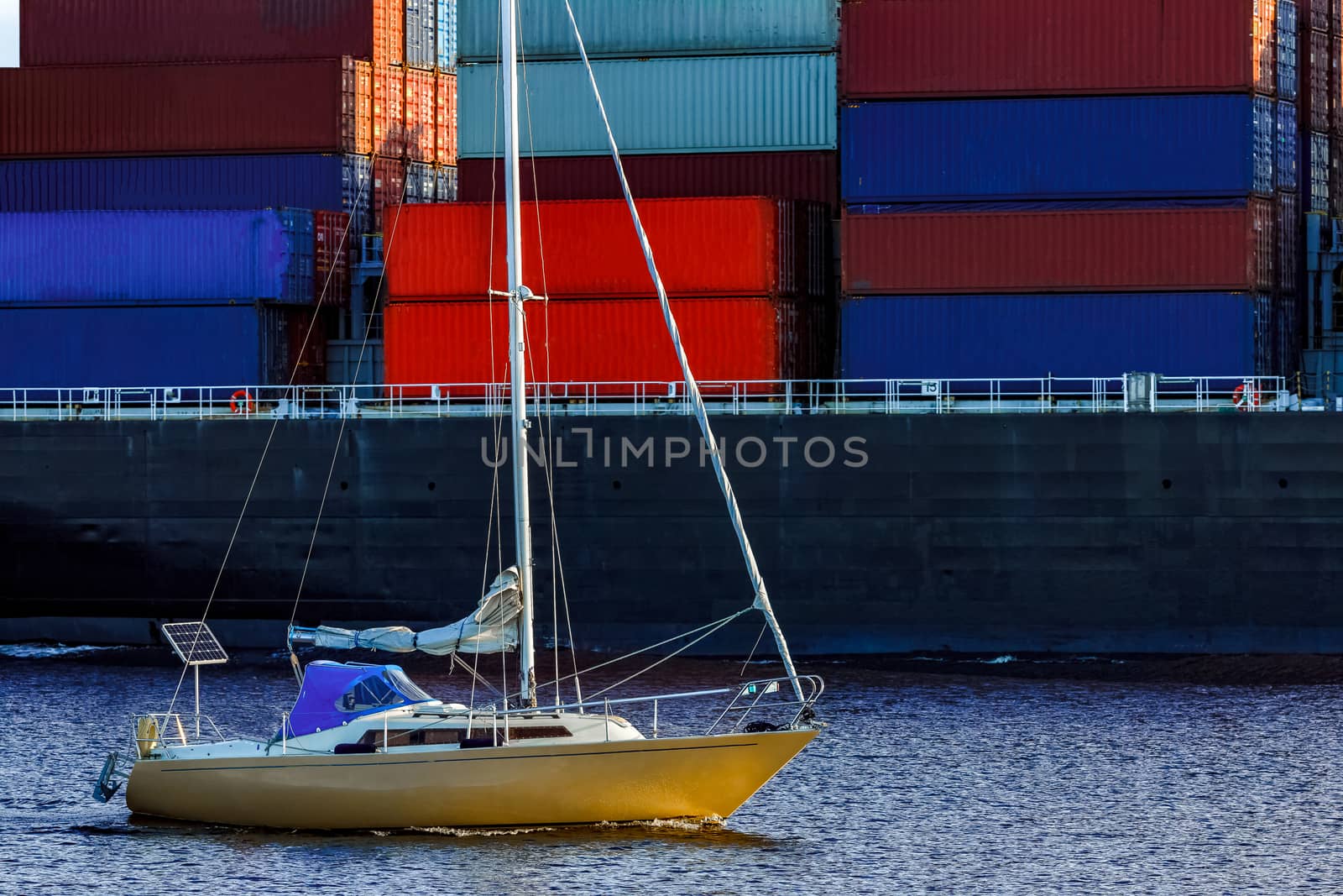 Yellow sailboat against cargo ship by sengnsp