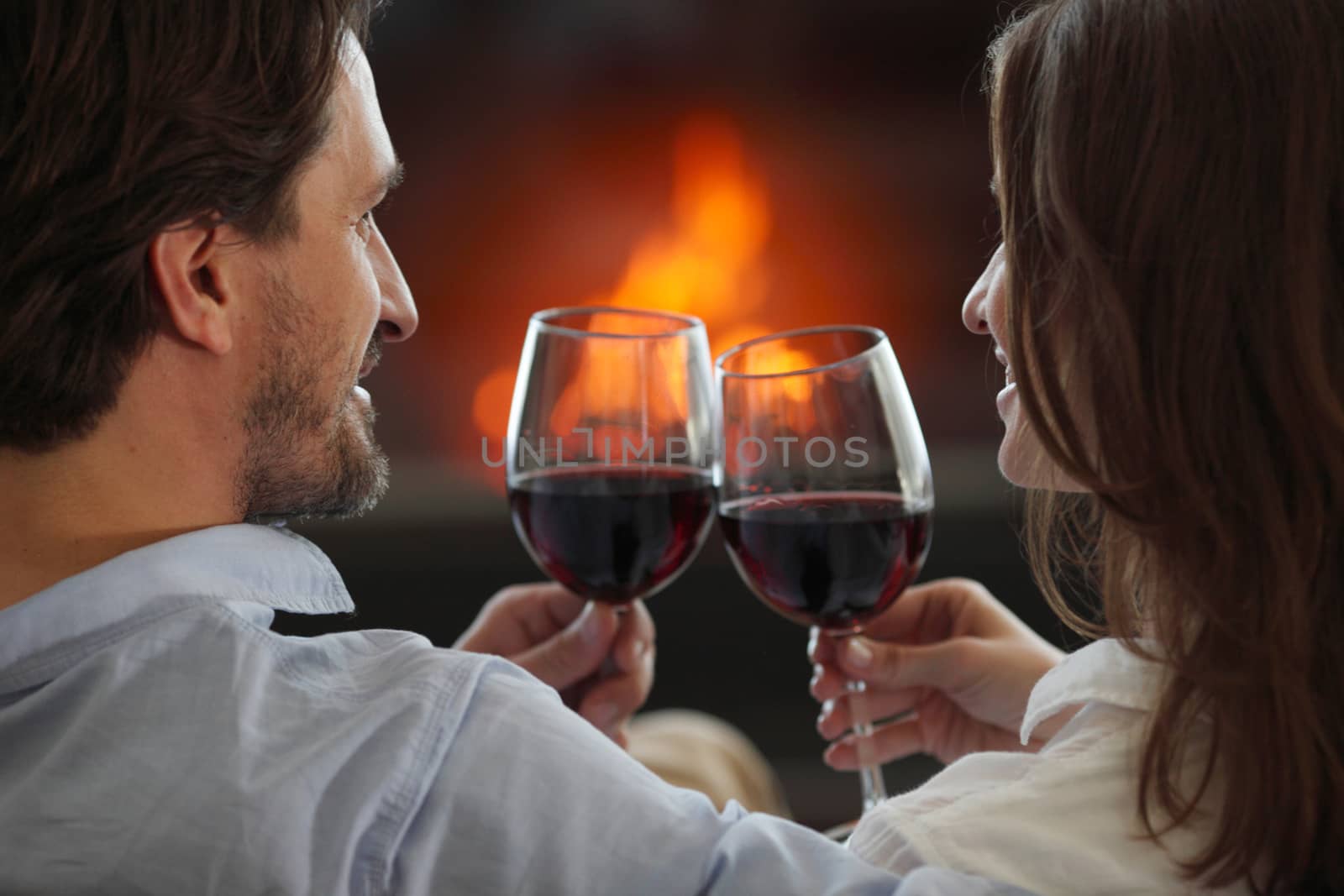 Romantic couple drinking wine at home near fireplace