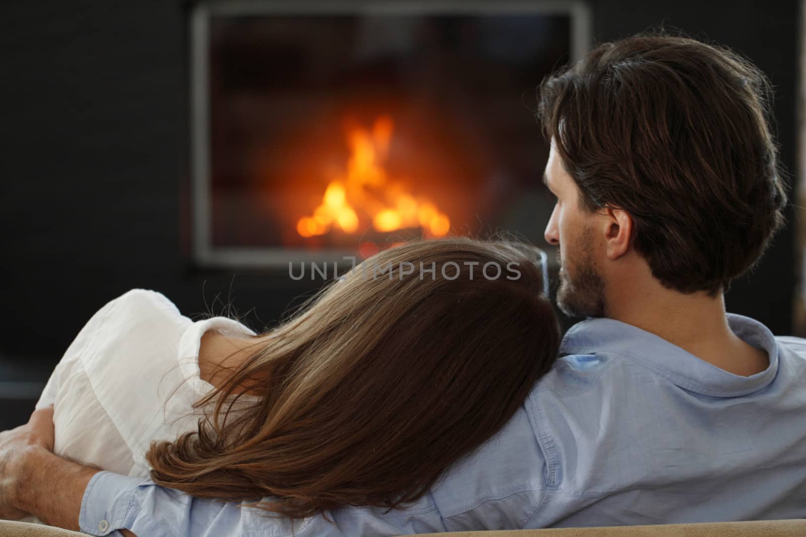 Romantic couple drinking wine at home near fireplace