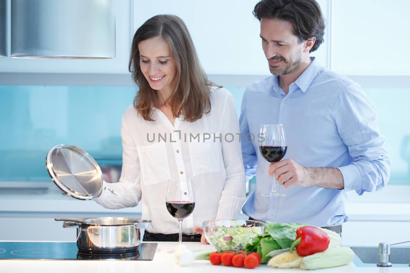 Portrait of a couple having a glass of red wine while cooking dinner