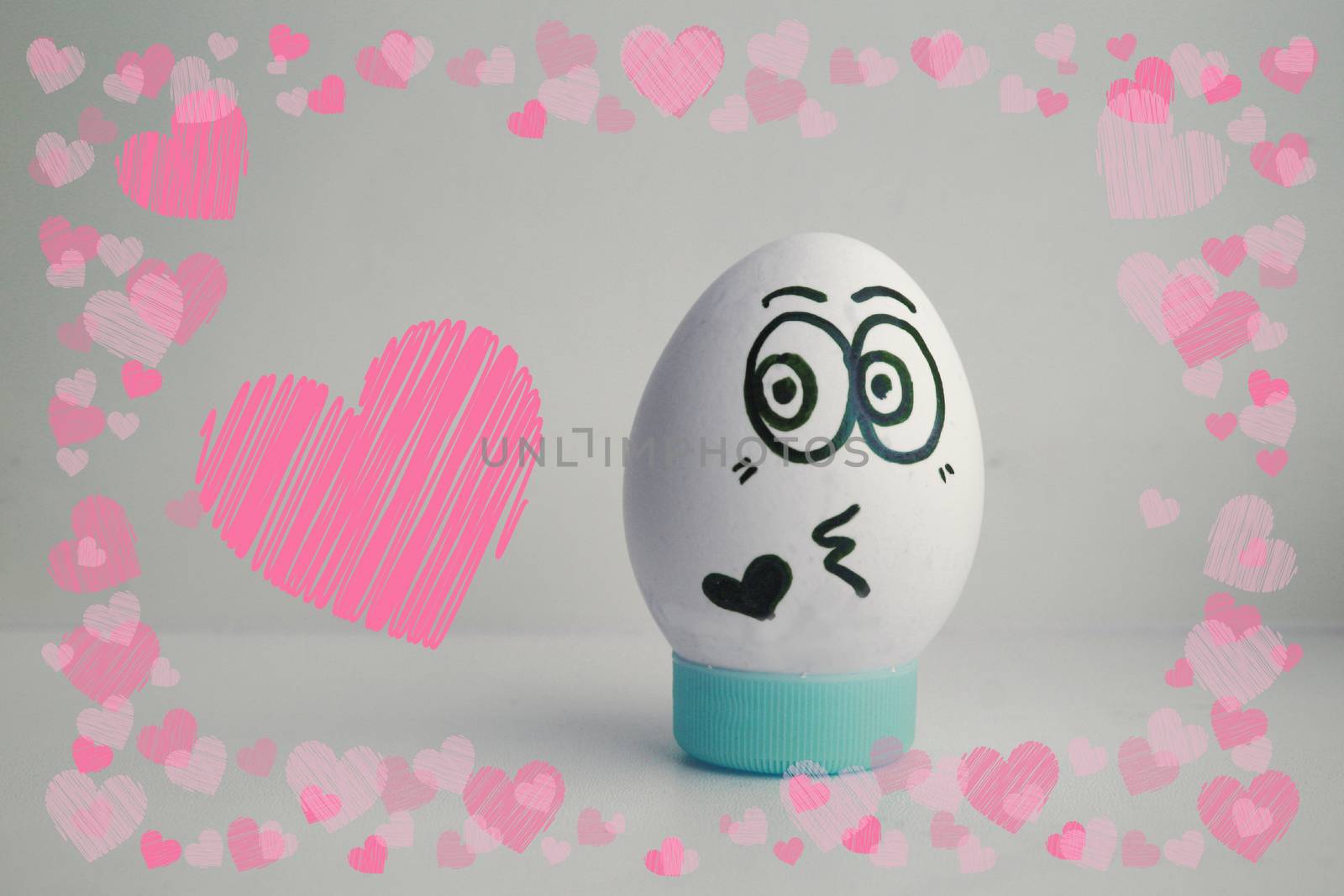 The egg is funny with the face on the stand. Concept: love feelings. Photo for your design on a white background Frame of hearts. love