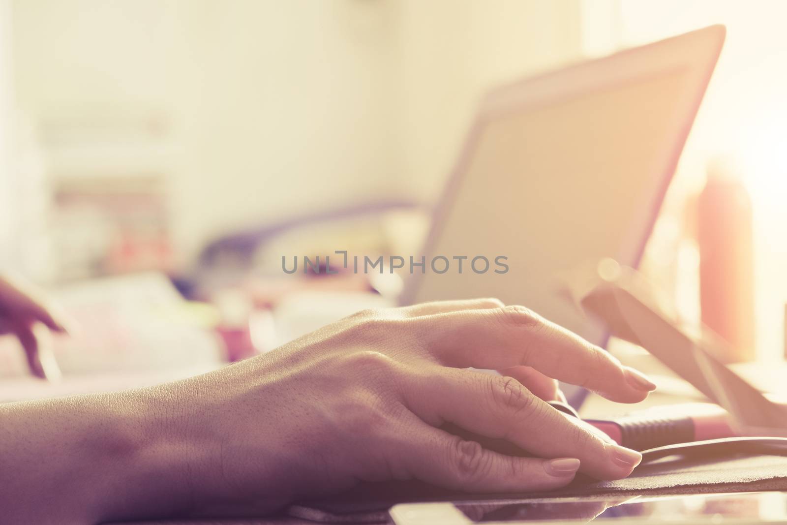 Close-up of female hands using laptop computer, working on laptop with flare light background. Searching Internet ,Businesswoman working at home office
