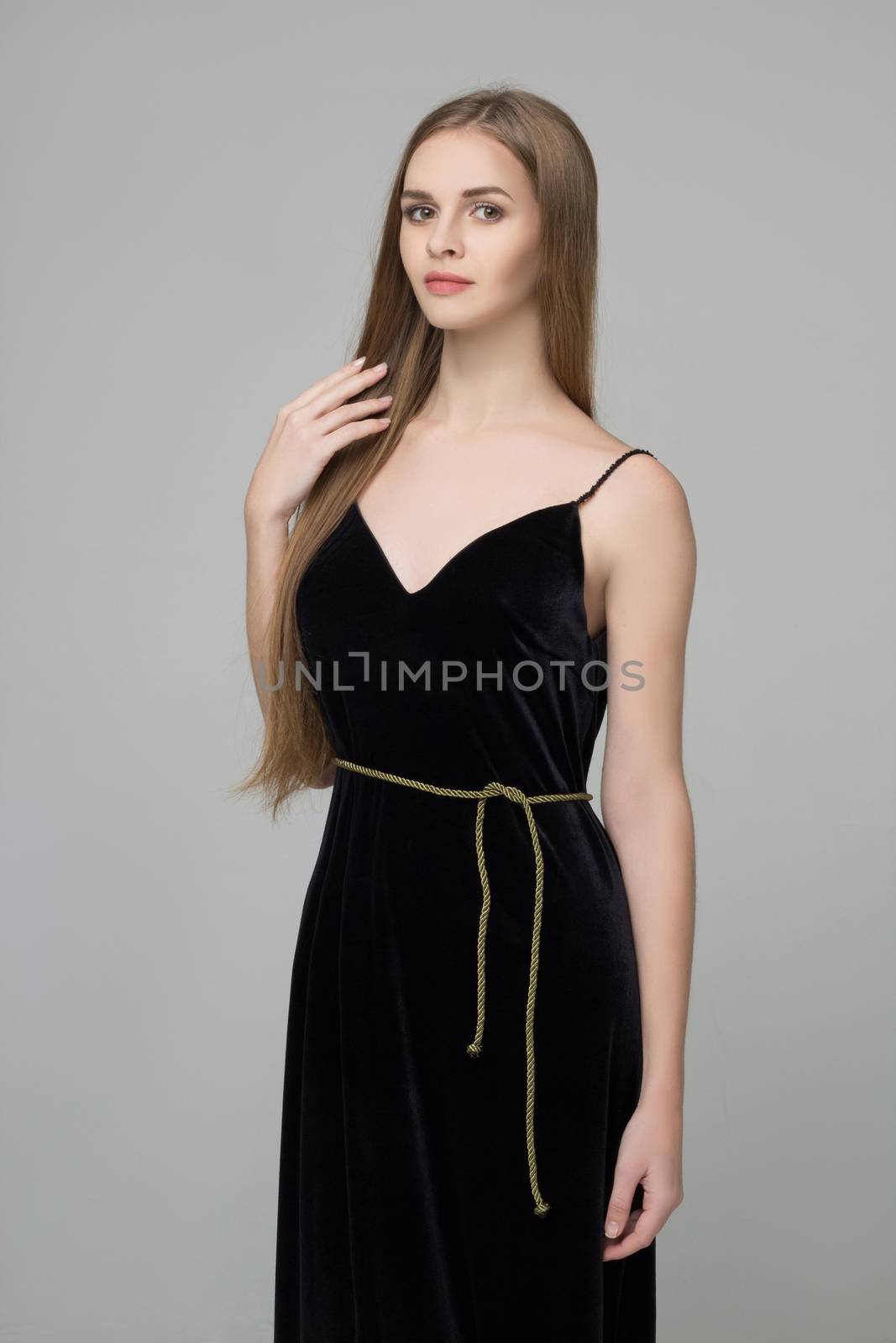 Young beautiful long-haired girl stands in black dress