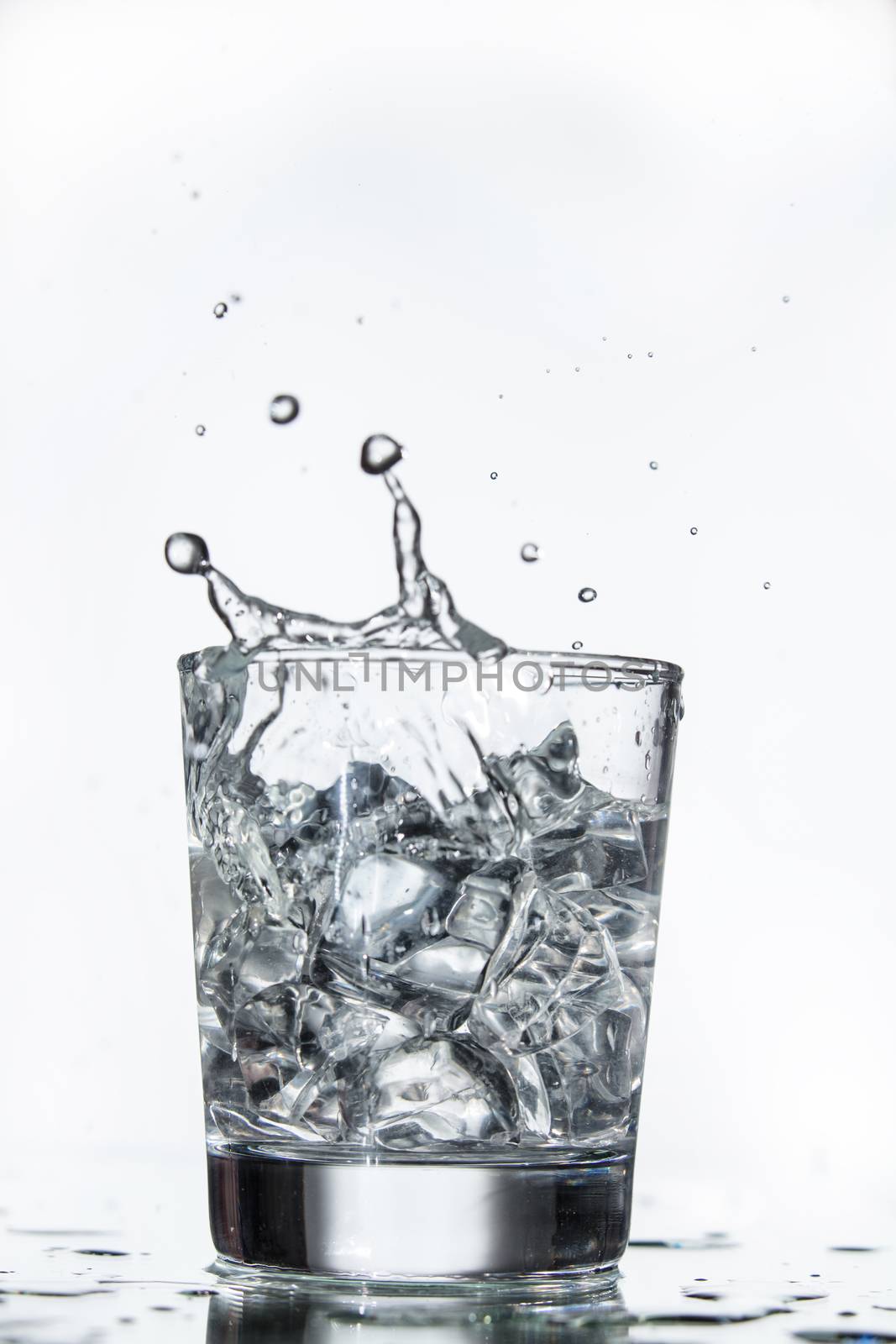 Glass with water and falling crystals of ice