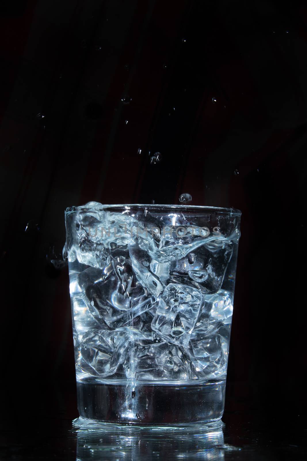 Glass with water and falling crystals of ice