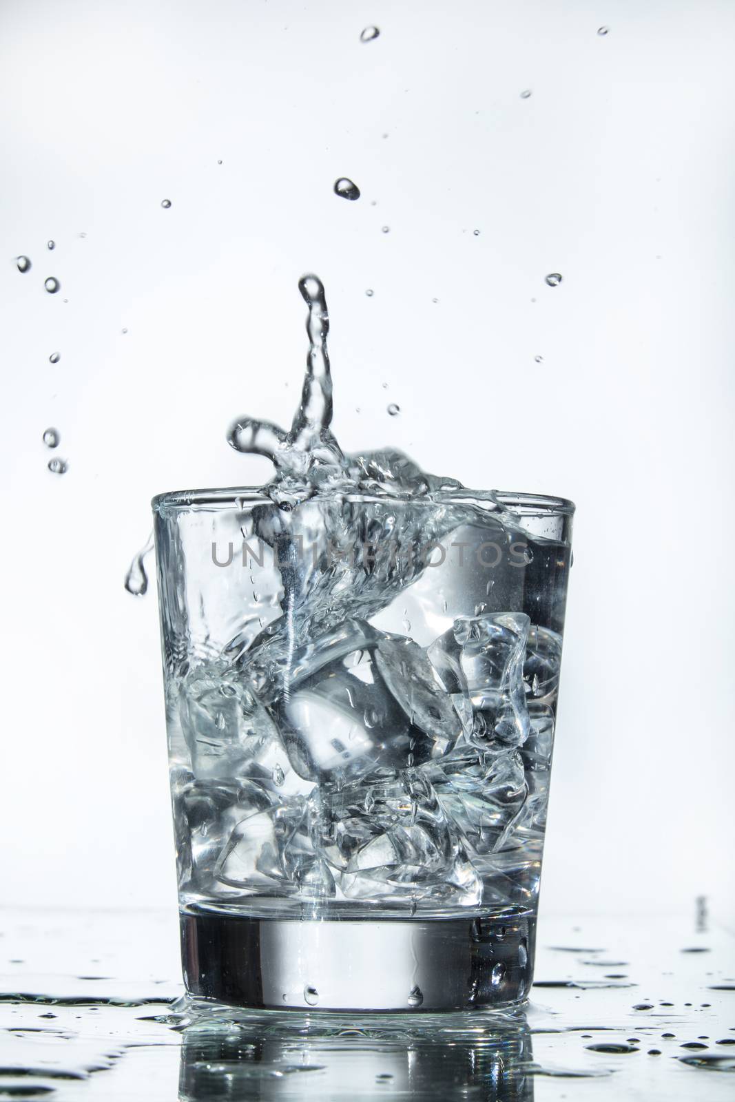 Glass with water and falling crystals of ice