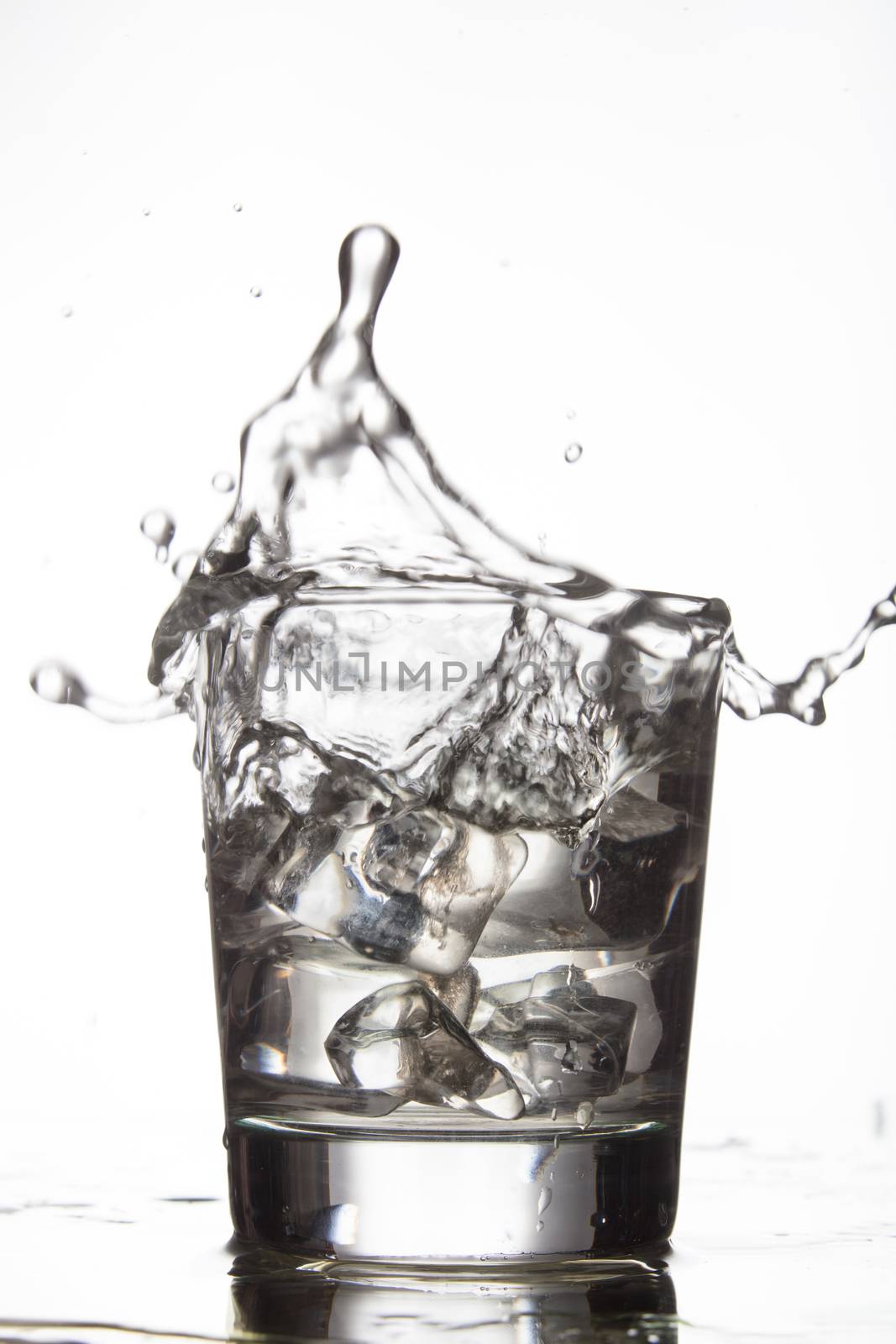 Glass with water and falling crystals of ice