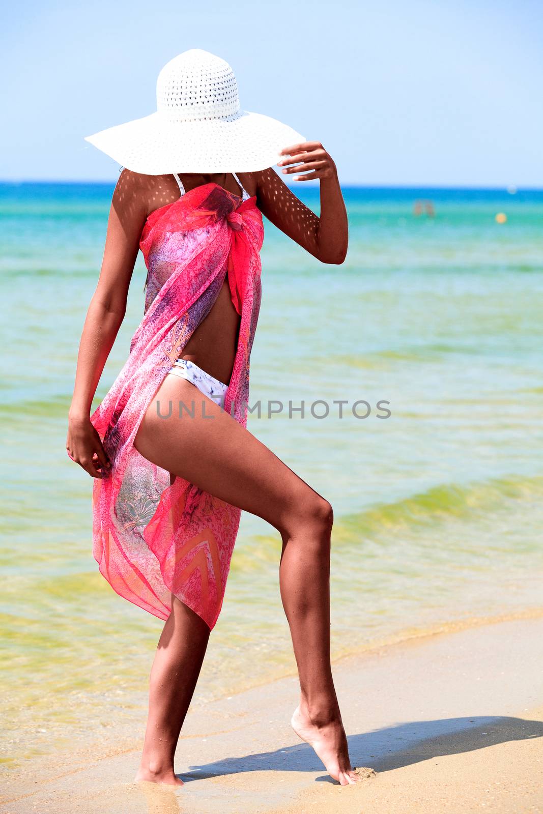 Slim tanned woman posing on a sea beach by Nobilior