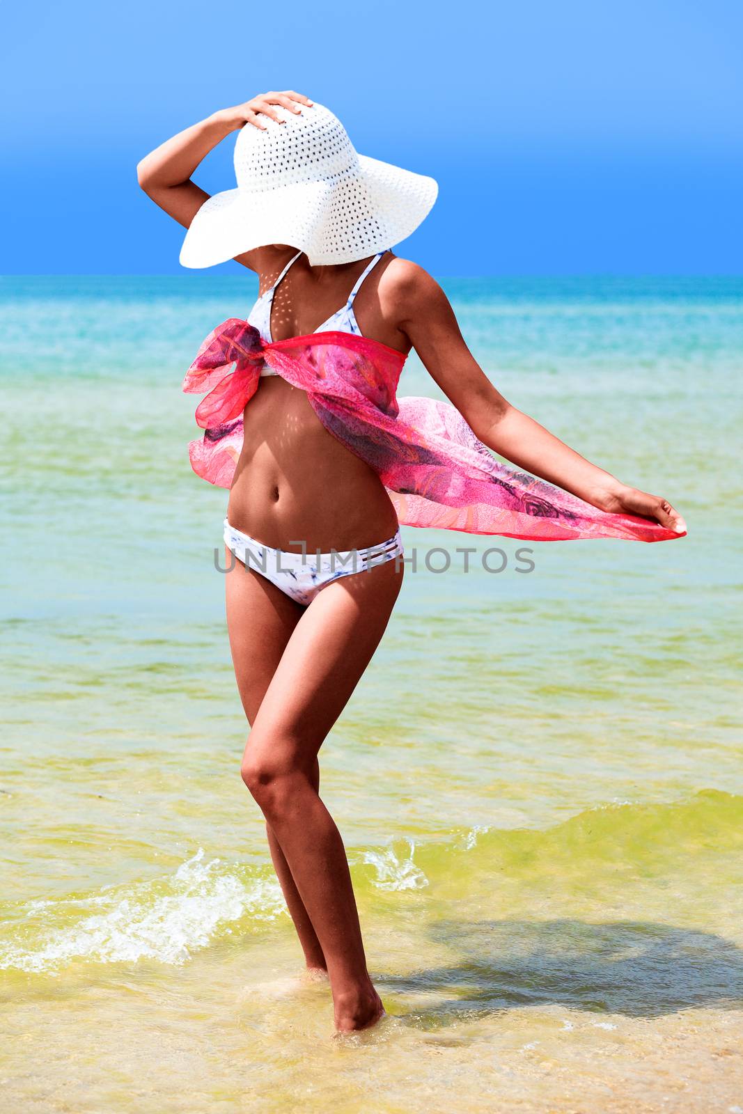 Slim tanned woman posing on a sea beach