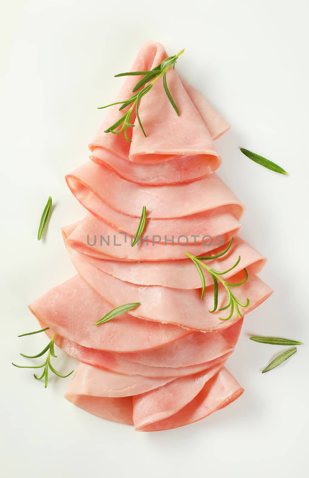 thin slices of ham with fresh rosemary leaves on white background