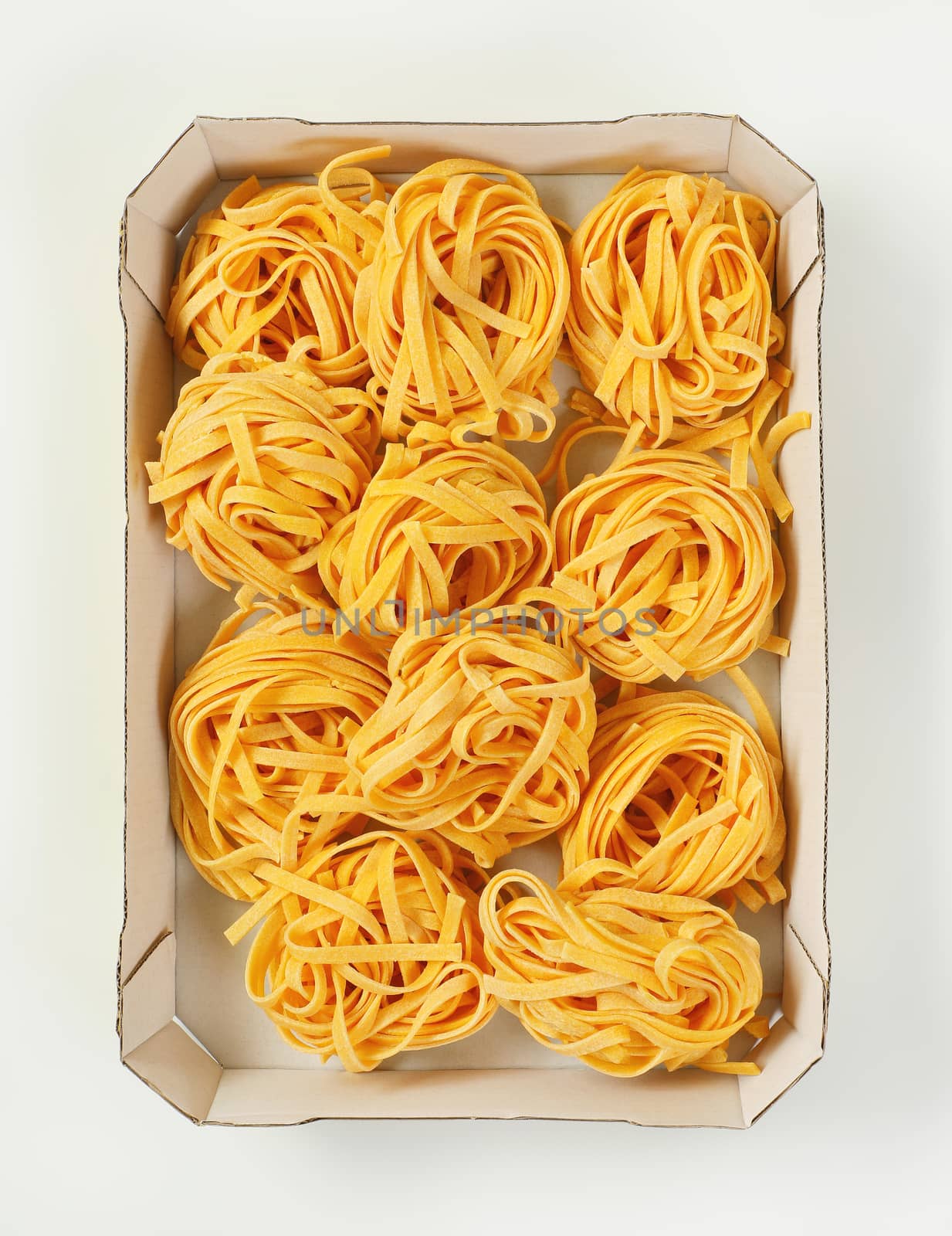 box of dried ribbon pasta bundles on white background