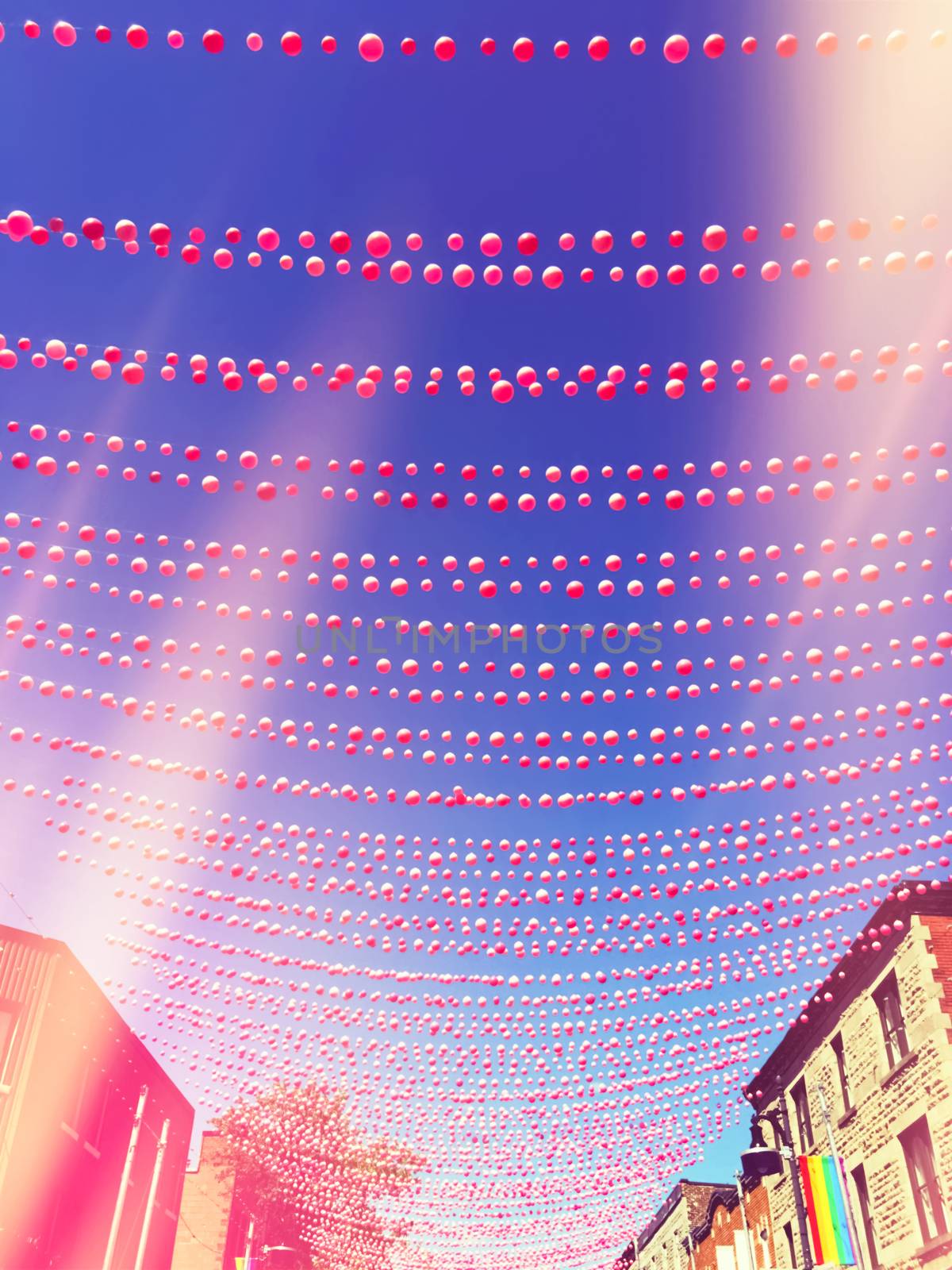 Retro style image of a street in gay neighborhood decorated with pink balls, with light leaks effect. Annual summer installation in gay village on Ste-Catherine street, Montreal (Quebec, Canada).