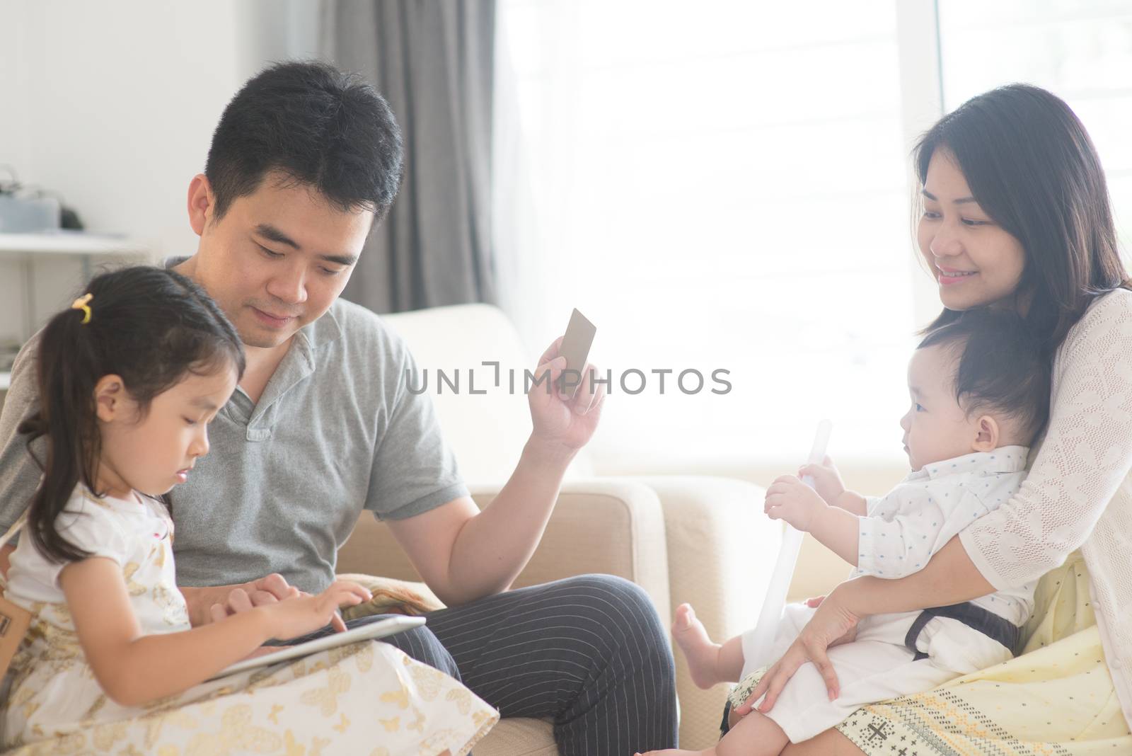 Online shopping with tablet pc and credit card. Happy Asian family at home, natural living lifestyle indoors.
