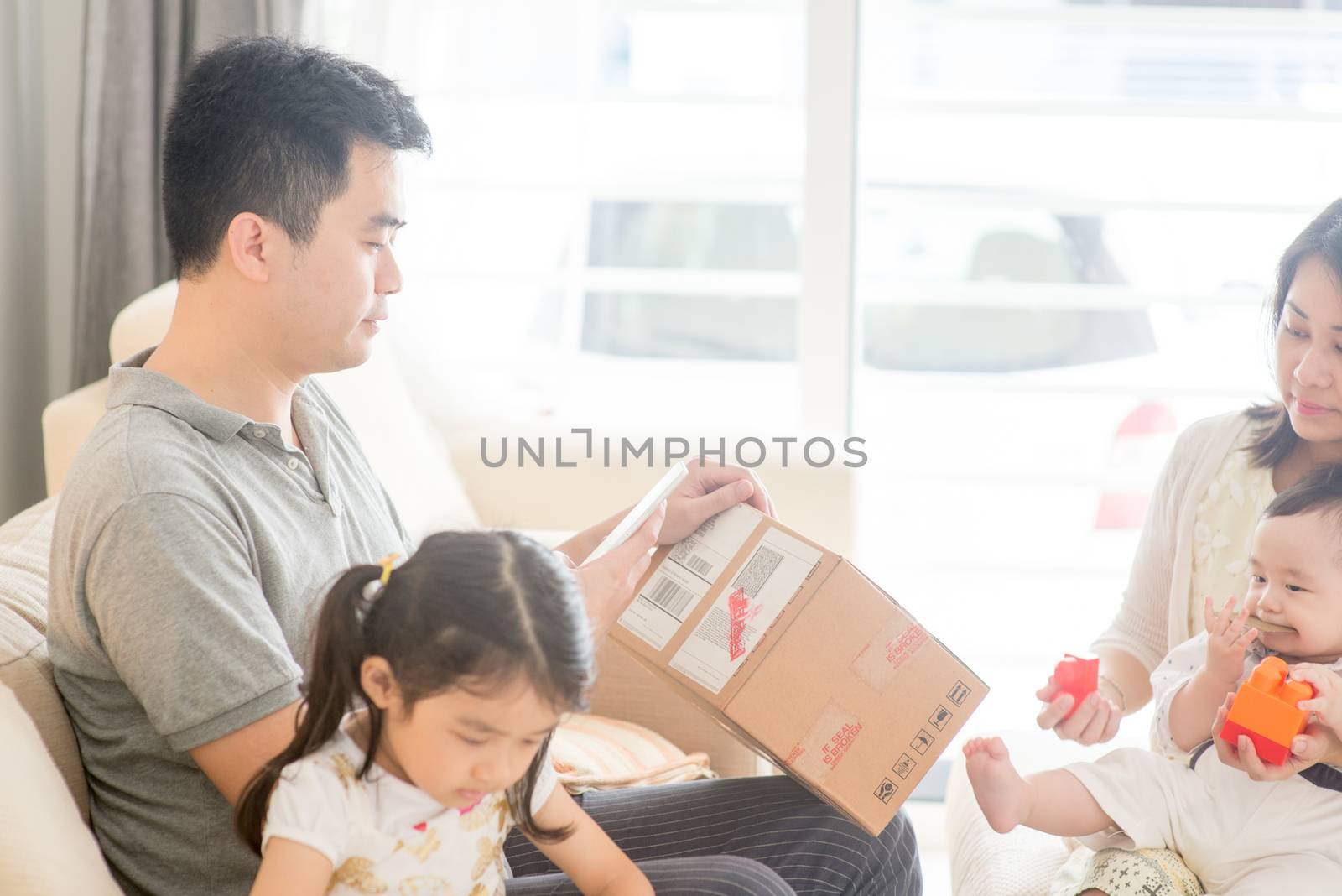 Father scanning QR code with smart phone. Happy Asian family at home, natural living lifestyle indoors.