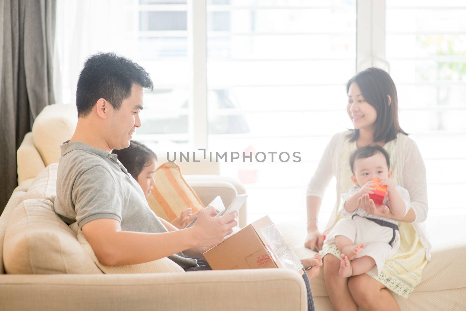 Chinese man scanning QR code with smart phone. Happy Asian family at home, natural living lifestyle indoors.