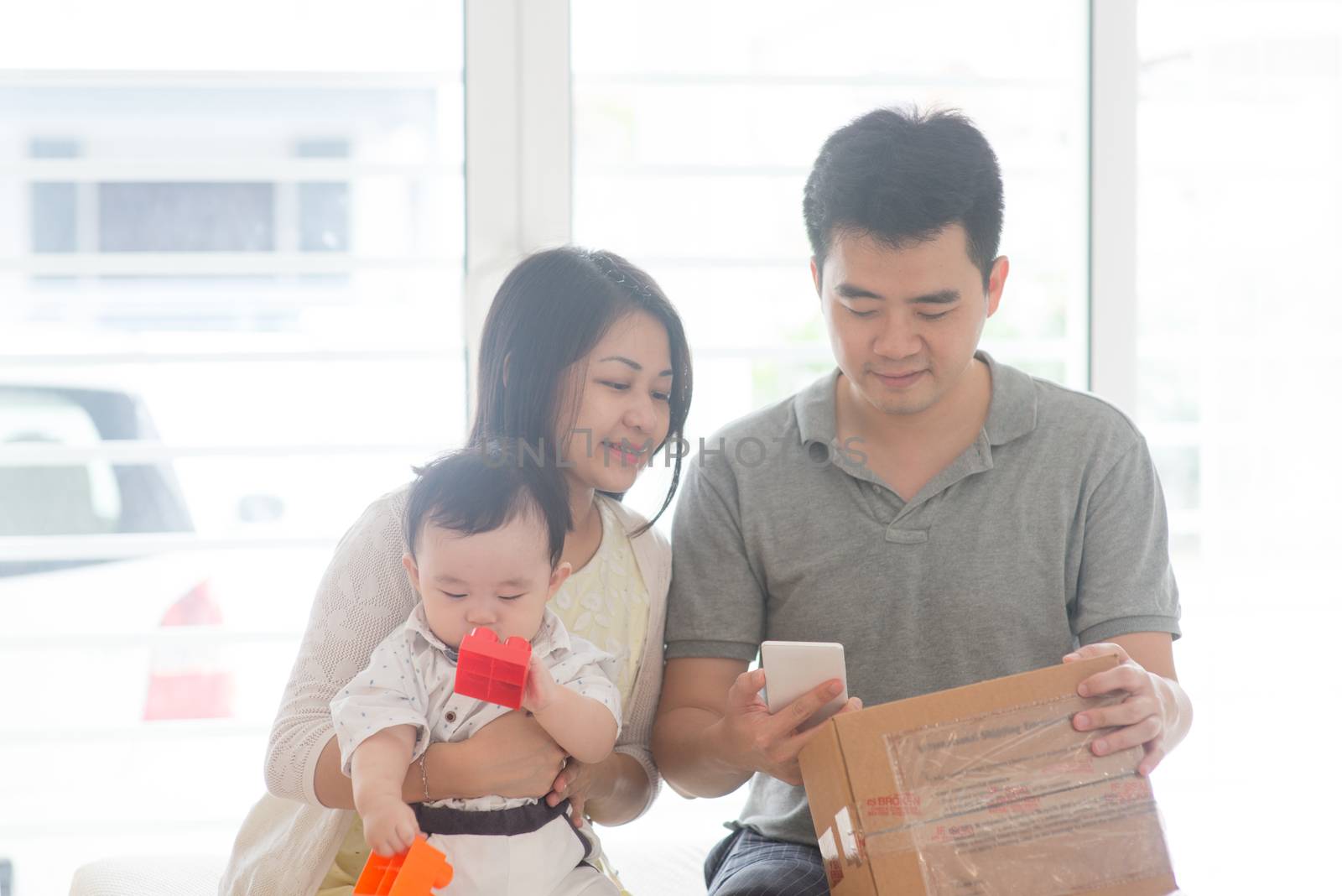 Chinese father scanning QR code with smart phone. Happy Asian family at home, natural living lifestyle indoors.